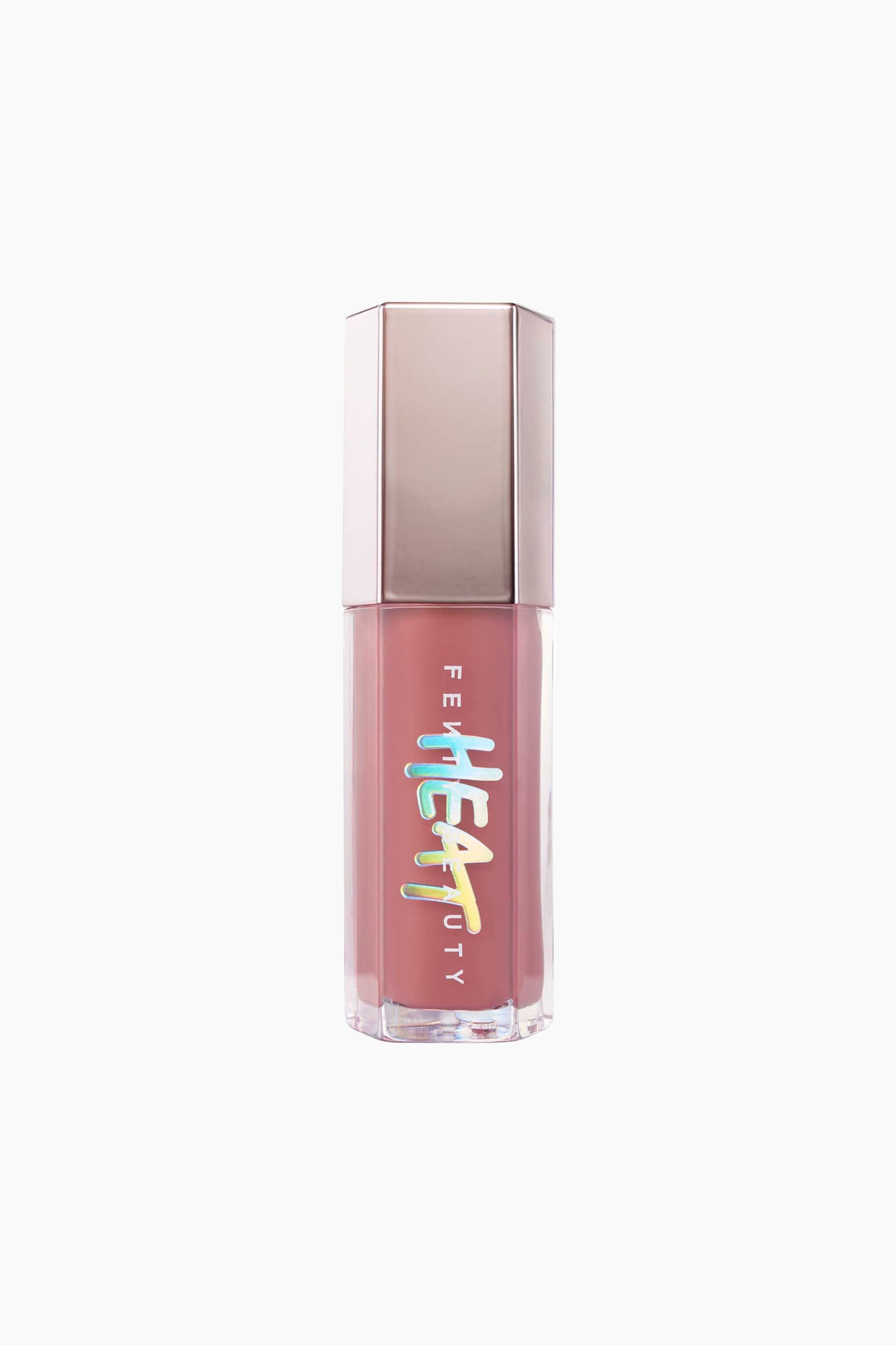 Visa större bild: Gloss Bomb Heat Universal Lip Luminizer + Plumper står upprätt och visar upp en sexkantig genomskinlig tub fylld med ett dammrosa gloss, toppad med en metallisk roséguldfärgad sexkantig kork. Tubens framsida visar det vertikala vita varumärket "FENTY BEAUTY" med den framträdande, iriserande holografiska "HEAT"-logotypen ovanpå.