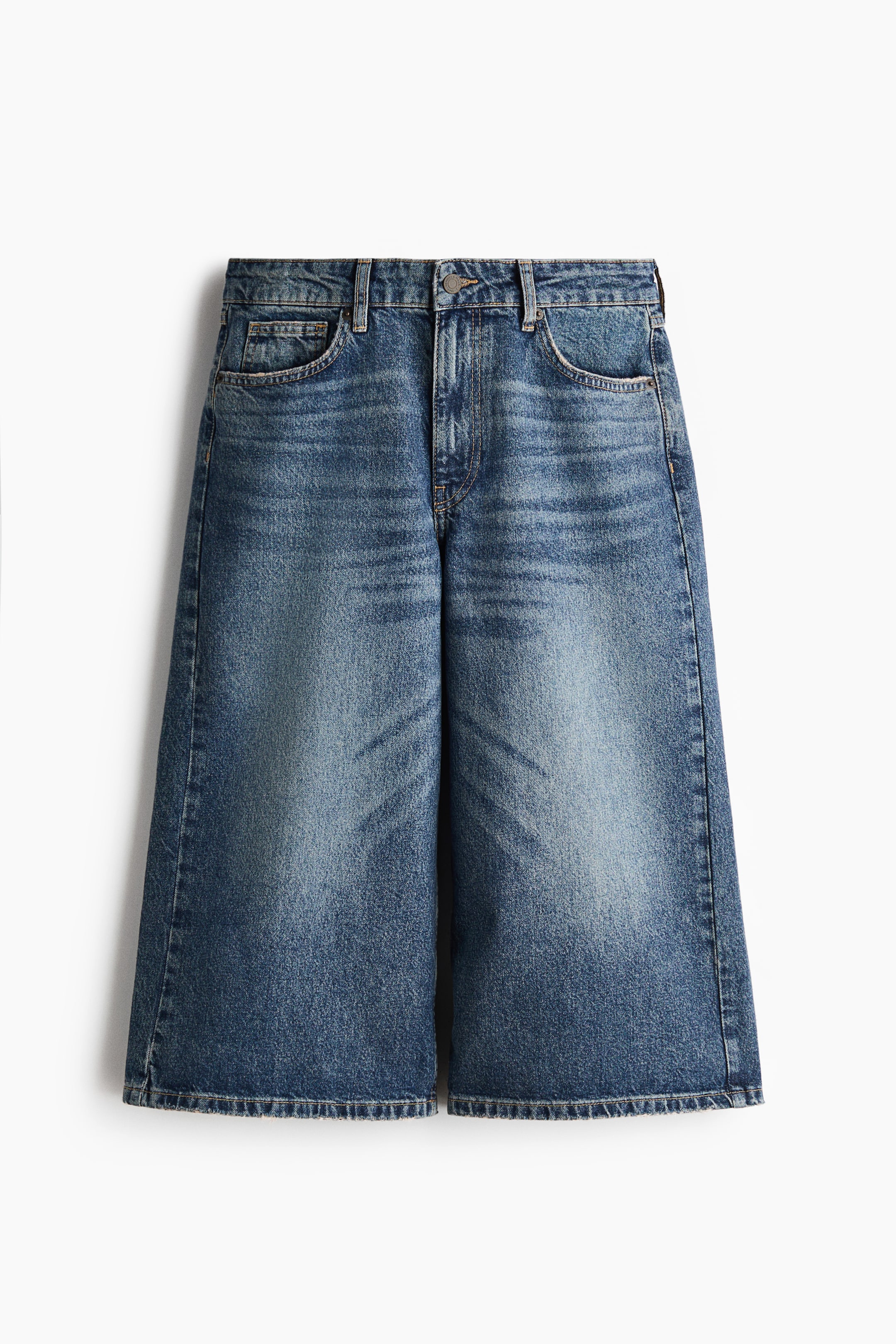 Büyük resmi görüntüle: Önden bakıldığında, 5 cepli culotte kot pantolonlar, sert pamuklu denim üzerine soluk mavi bir yıkama sergiliyor. Normal bel, fermuarlı ve düğmeli kapanış ile öne çıkıyor. Belden kalçaya kadar normal kesim, uyluktan paçaya kadar geniş kesim ve geniş bacak yapısına sahip.