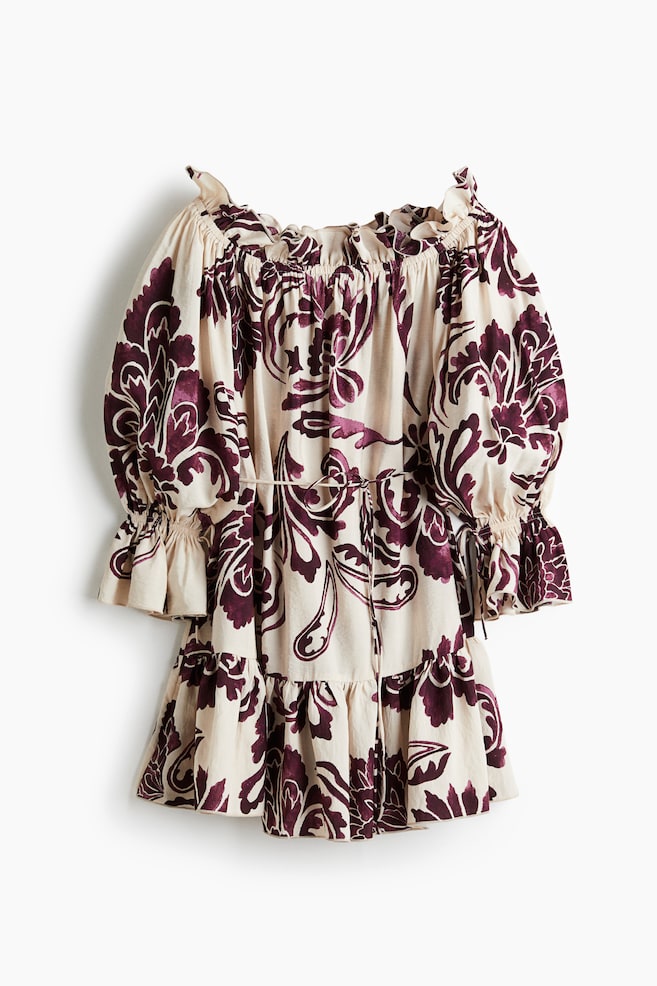 An off-the-shoulder dress, presented in a FRONT view, is featuring a beige base adorned with a large, dark purple floral and paisley pattern. It is designed with an elasticized ruffled neckline, voluminous elbow-length sleeves showcasing elasticated ruffled cuffs and tie details, a drawstring cinched waist, and a tiered, ruffled hem. - 1