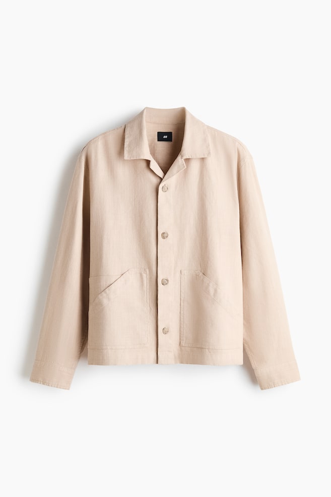 A light beige, linen-textured jacket is facing the front, featuring a camp collar, a four-button closure, and long sleeves. Two large patch pockets with diagonal openings are positioned on the lower front of the straight-hemmed design. - 1