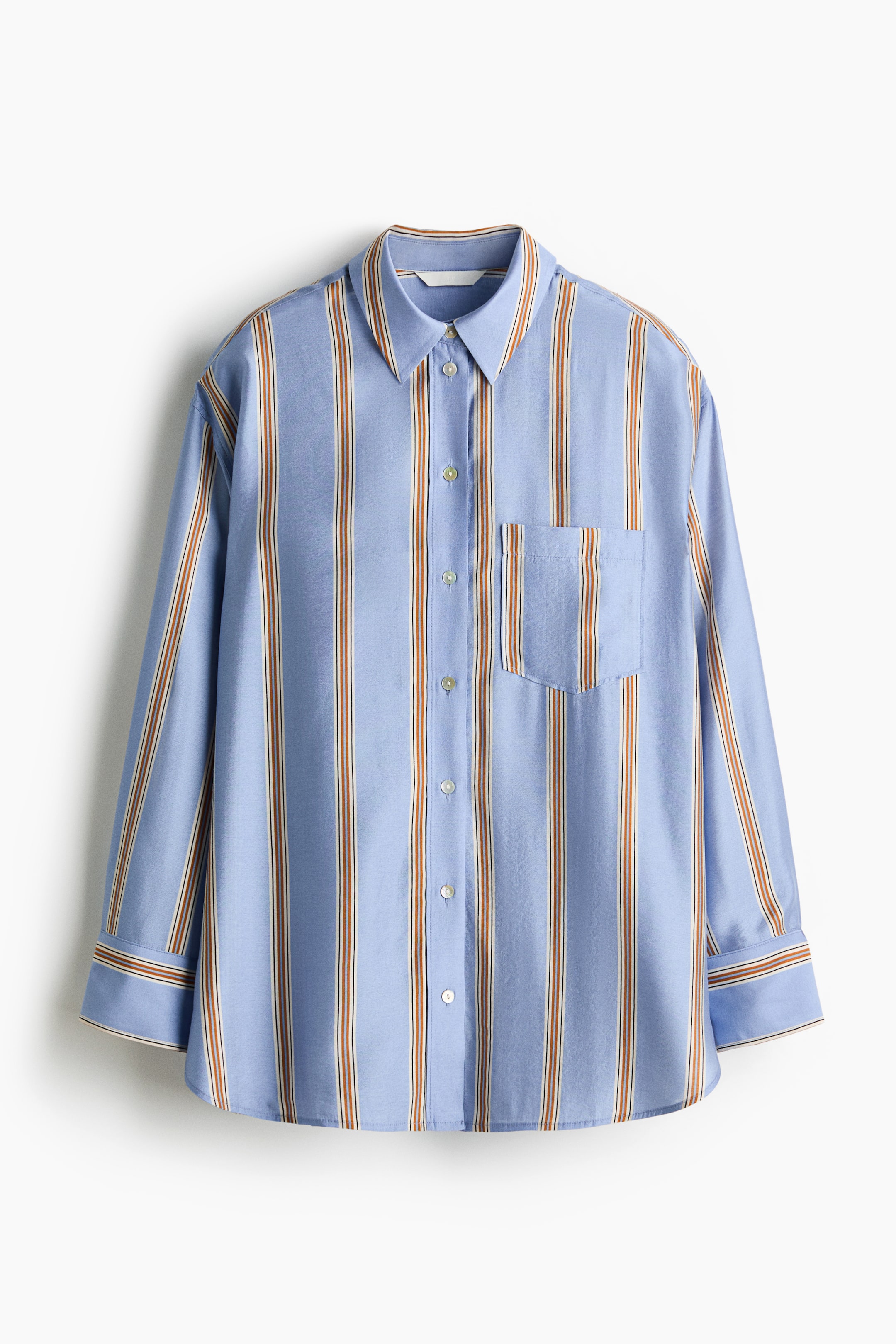 Se større billede: En oversized skjorte vises forfra og er udført i et blåt vævet stof med lodrette brune og hvide striber. Den har en krave, knaplukning foran, en åben brystlomme, let sænkede skuldre, lange ærmer med knapmanchetter og en ærmesprække med en forbindelsesknap samt en lige skåret kant med afrundede sideslidser.