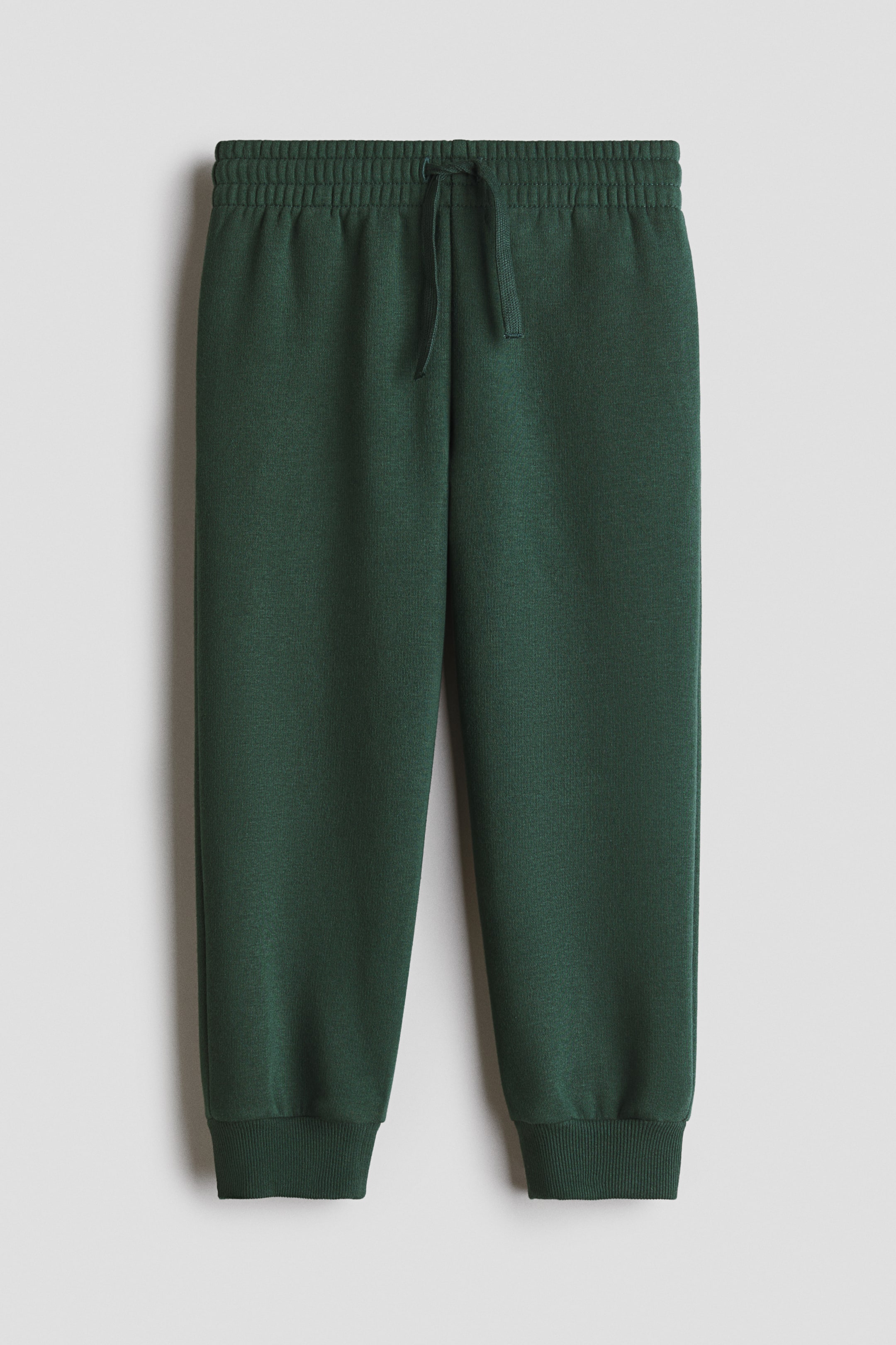 View larger image: Dark green sweatpants feature an elasticated waistband with a drawstring tie and ribbed cuffs, shown from the front.