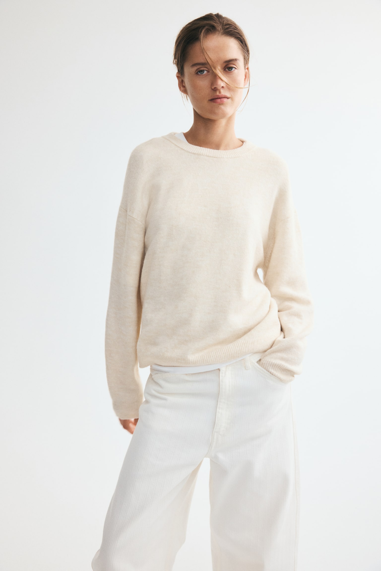 A light beige jumper is showcased from the front, boasting a soft knit texture, a round ribbed neckline, dropped shoulders, long sleeves, and ribbed cuffs and hem. - 1
