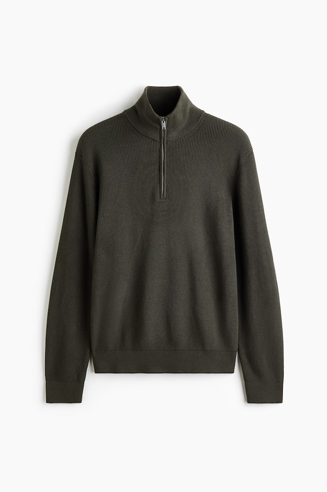 Sweter w ciemnym oliwkowozielonym kolorze, wykonany z dzianiny o prÄ
żkowanym splocie, przedstawiono od przodu. Model ma stójkÄ z zapiÄciem na póÅzamek w srebrnym odcieniu. Sweter z dÅugim rÄkawem ma prosty dóŠoraz delikatne prÄ
żkowanie przy koÅnierzu, mankietach i u doÅu. - 1