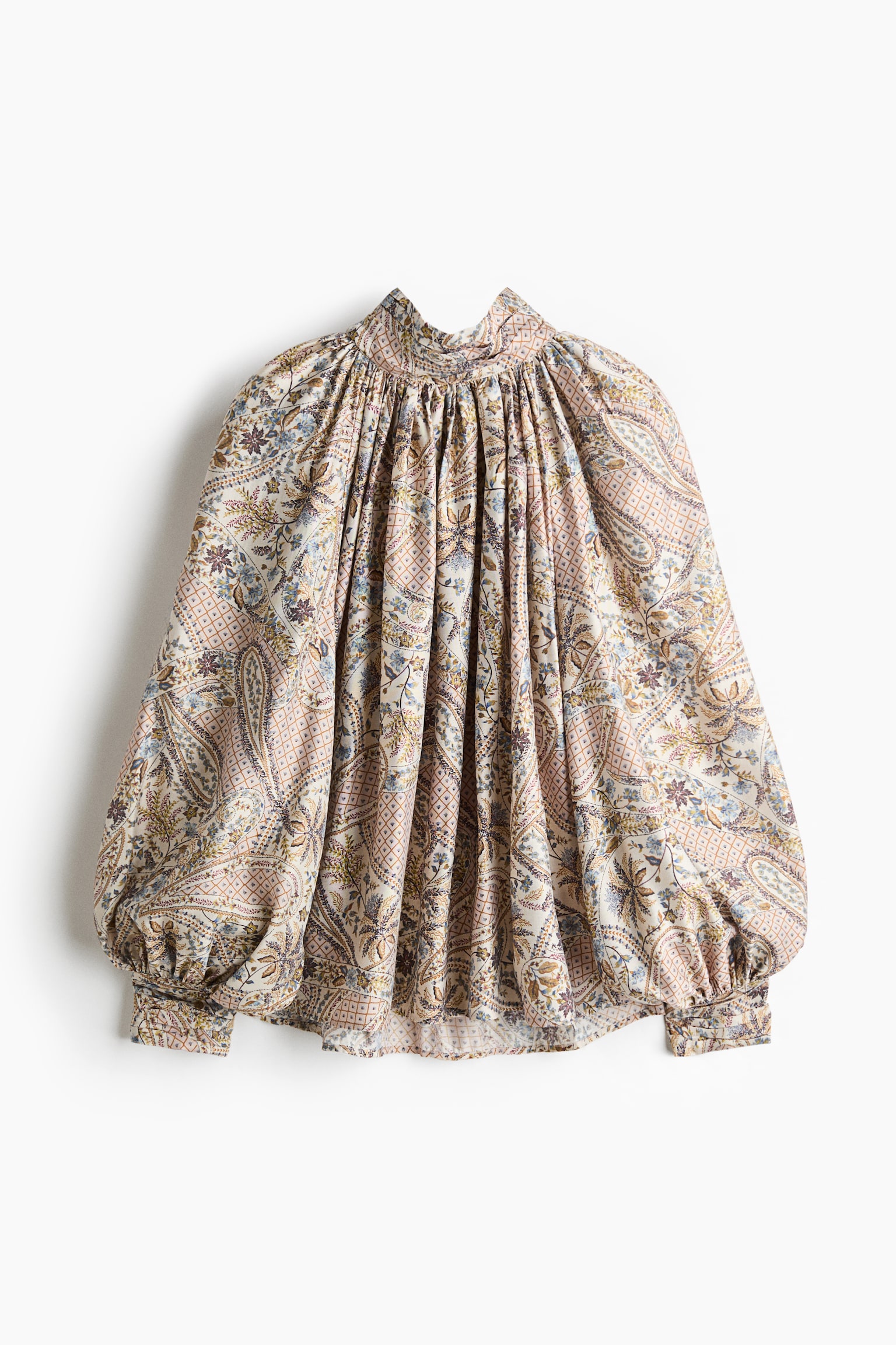 Cette vue de face prÃ©sente une blouse surdimensionnÃ©e en tissu tissÃ©, ornÃ©e dâun imprimÃ© paisley multicolore complexe. La blouse met en valeur un col montant haut froncÃ© avec des fronces Ã  la base, se dÃ©ployant dans une silhouette volumineuse avec de longues manches ballon raglan et de larges poignets.