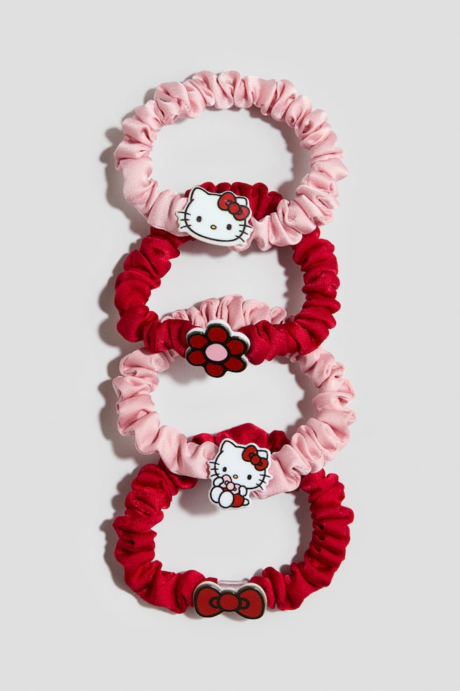 Fyra rynkade satinscrunchies i vÃ¤xlande ljusrosa och djuprÃ¶tt Ã¤r sammanlÃ¤nkade vertikalt och visar sina framsidor. De rosa scrunchiesarna pryds av Hello Kitty-berlocker, medan de rÃ¶da scrunchiesarna visar en rÃ¶d blomma med rosa mitt och en rÃ¶d rosettdetalj. - 1