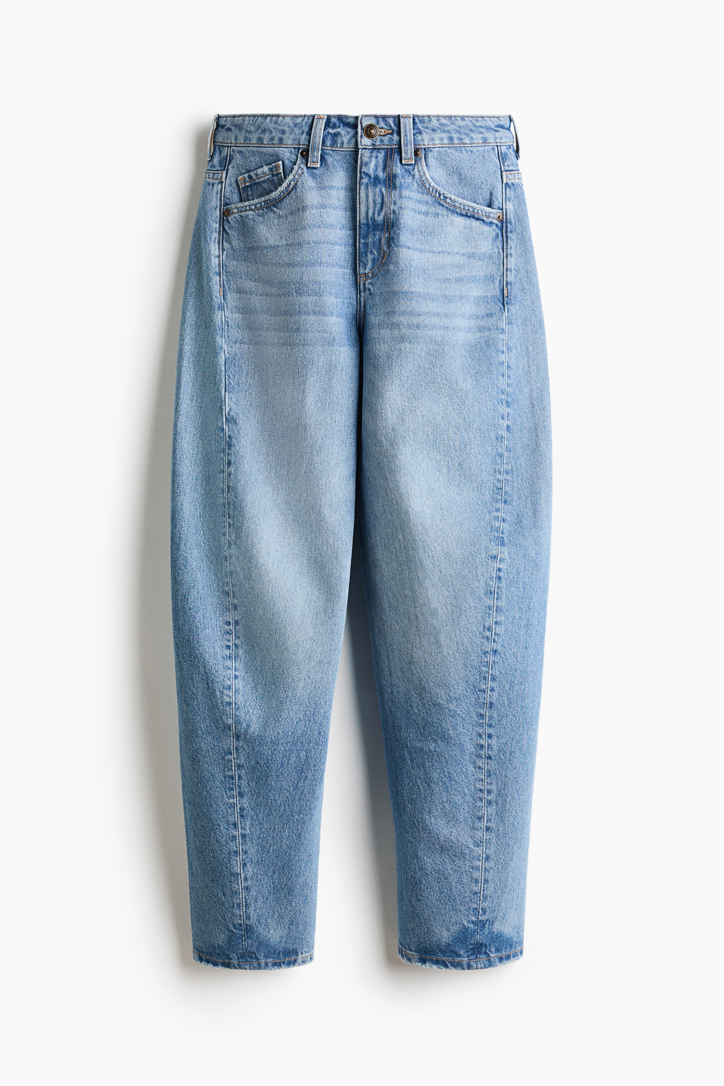 These blue five-pocket jeans are shown from the front, featuring a regular waist and curved, voluminous legs with forward-facing side seams that taper slightly at the hems. They are styled with a slim patterned drawstring at the waist, along with a white crop top, an open cream overshirt, and light-coloured sneakers.