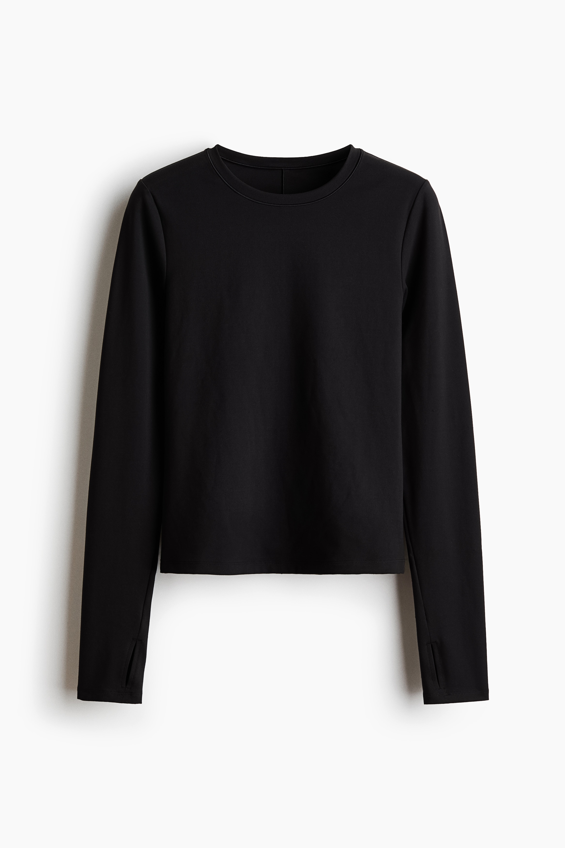 A black, form-fitting long-sleeve top featuring a vertical back seam and thumbhole cuffs is being worn by the model. The top is styled with a matching black gathered skirt.