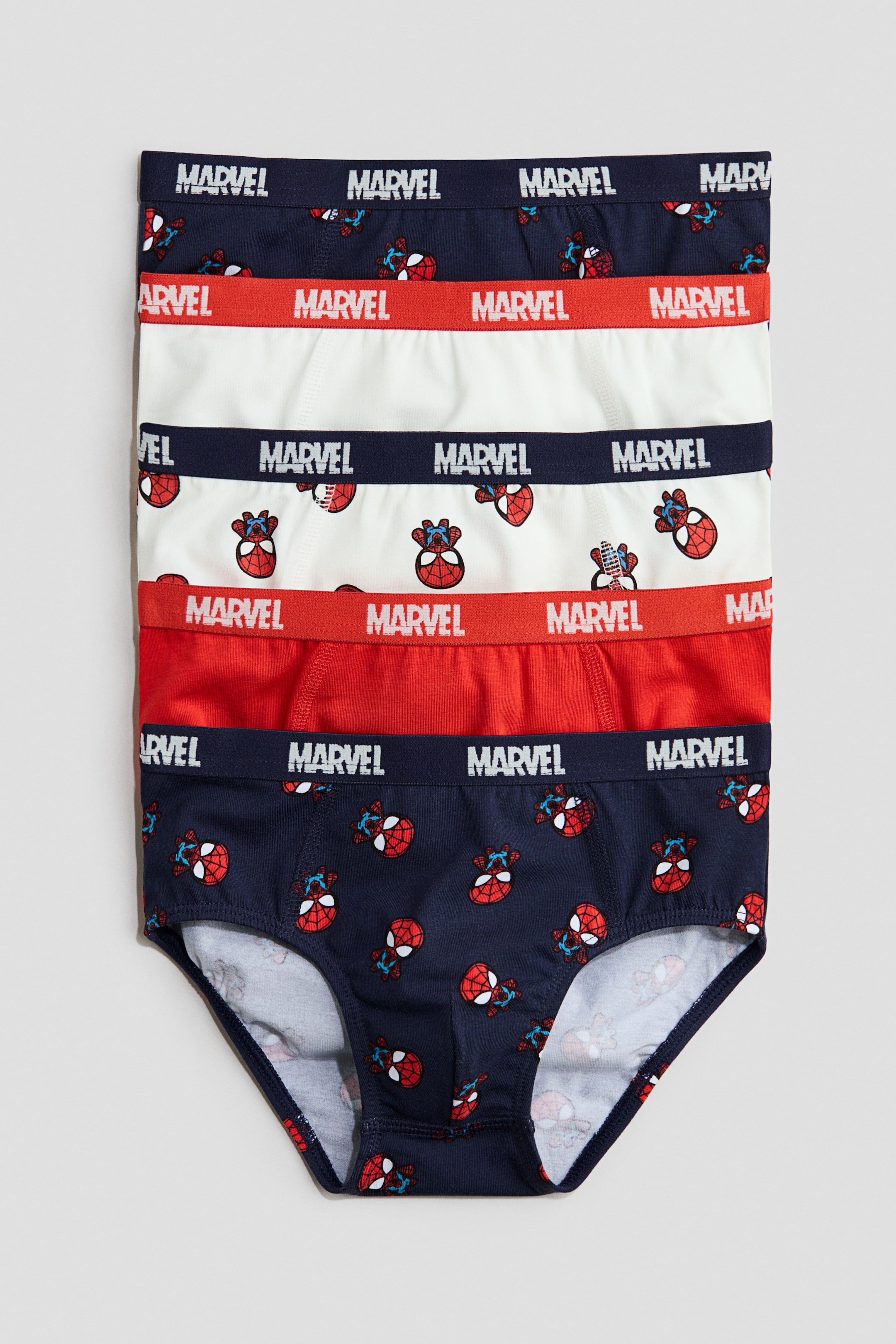 Agrandir l'image: Cinq slips pour garçons sont empilés, présentant l'avant. Les slips sont dotés d'une ceinture élastique portant le logo « Marvel » en blanc ou en bleu marine, et alternent entre un modèle uni rouge et un imprimé répétitif du personnage Spider-Man sur tissu bleu marine ou blanc.