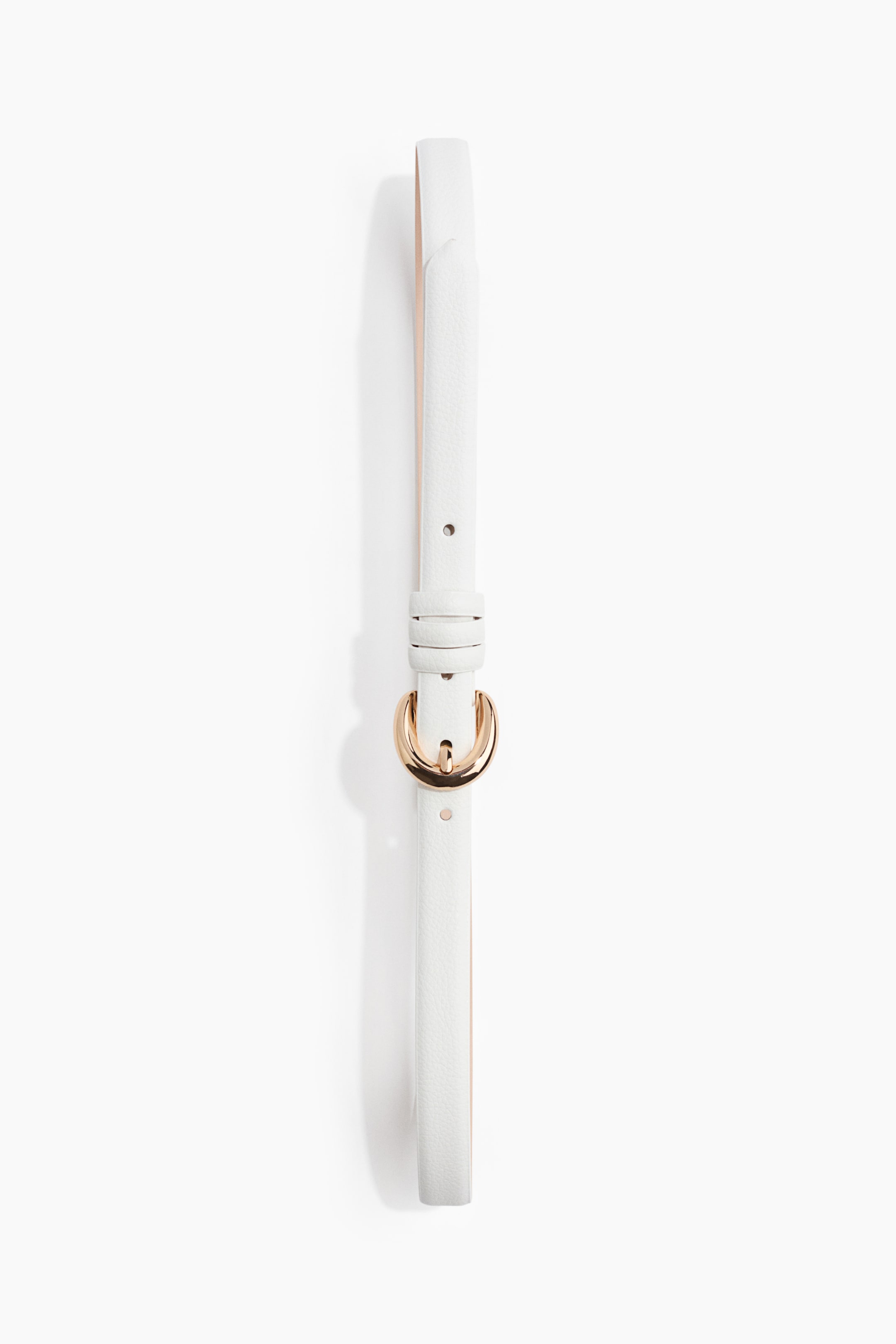 View larger image: A white belt is laid flat, showcasing a slim strap with a delicate pebbled texture and a gold-toned, crescent-shaped buckle. Several adjustment holes are visible along the strap, with a matching keeper loop securing the end.
