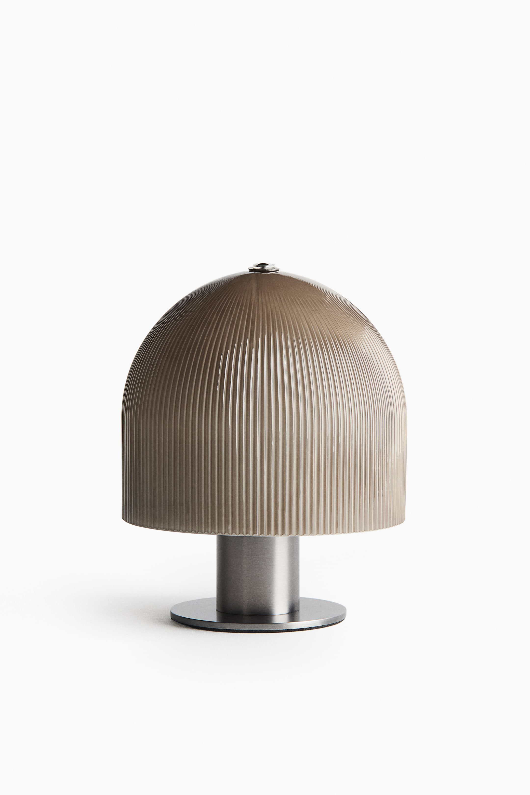 View larger image: This table lamp is shown from the front, featuring a mushroom-shaped design with a semi-translucent, ribbed dome shade in a muted taupe tone. The shade rests on a cylindrical brushed metal stem, which stands on a flat, circular base.