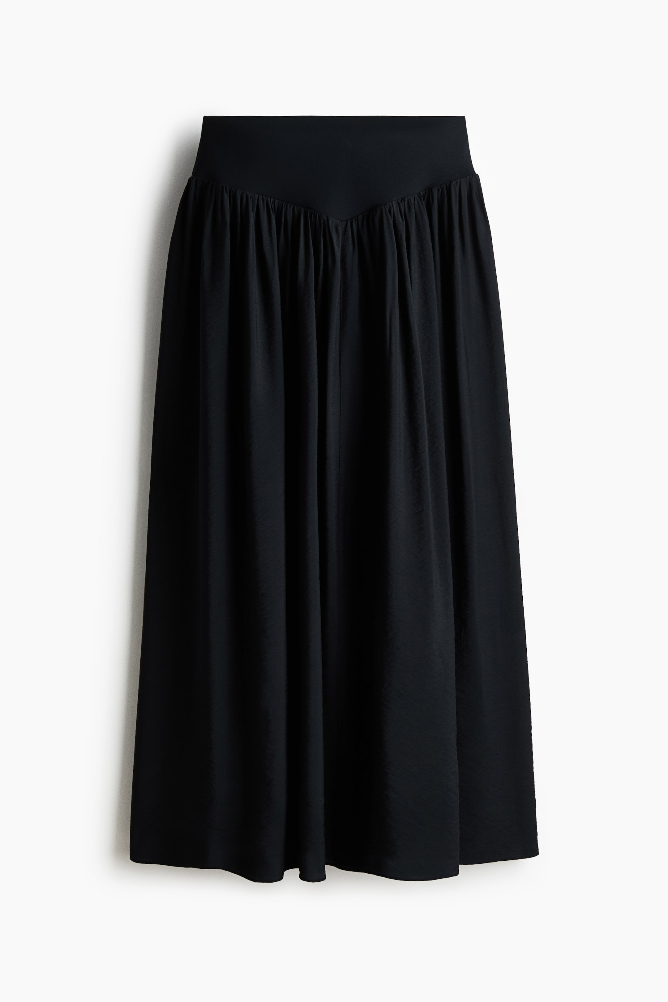 Ver imagen más grande: La falda negra está mostrando su PARTE DELANTERA, con una amplia y lisa cinturilla que presenta un detalle en forma de V en el centro. Los pliegues caen desde debajo del detalle en forma de V, y la falda de longitud midi fluye con un tejido sutilmente texturizado.