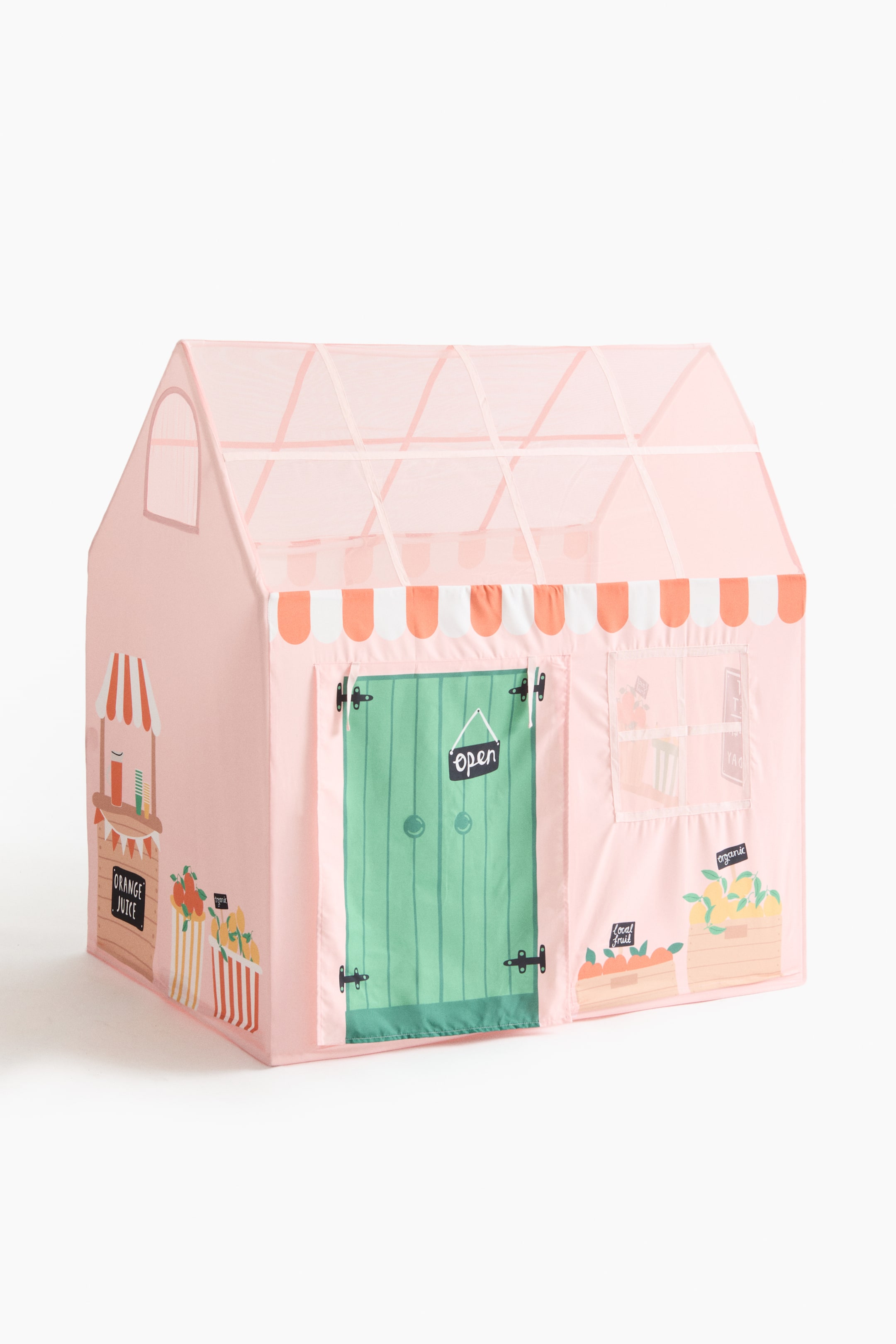 Agrandir l'image: Une tente de jeu rose présente son devant et son côté, affichant un design de stand de marché. Elle est dotée d'une porte verte avec un panneau "ouvert", d'un auvent rayé orange et blanc, d'un toit en pente rose translucide avec des poutres de soutien visibles, et d'illustrations d'un stand de jus d'orange et de caisses de fruits sur ses panneaux.