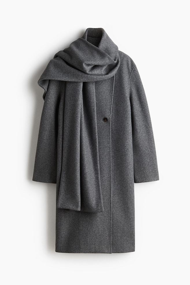 A dark grey coat is facing front, featuring a standing collar and a single dark button on its front. A matching dark grey scarf is draped around the coat's neck, with its ends falling down the front. - 1