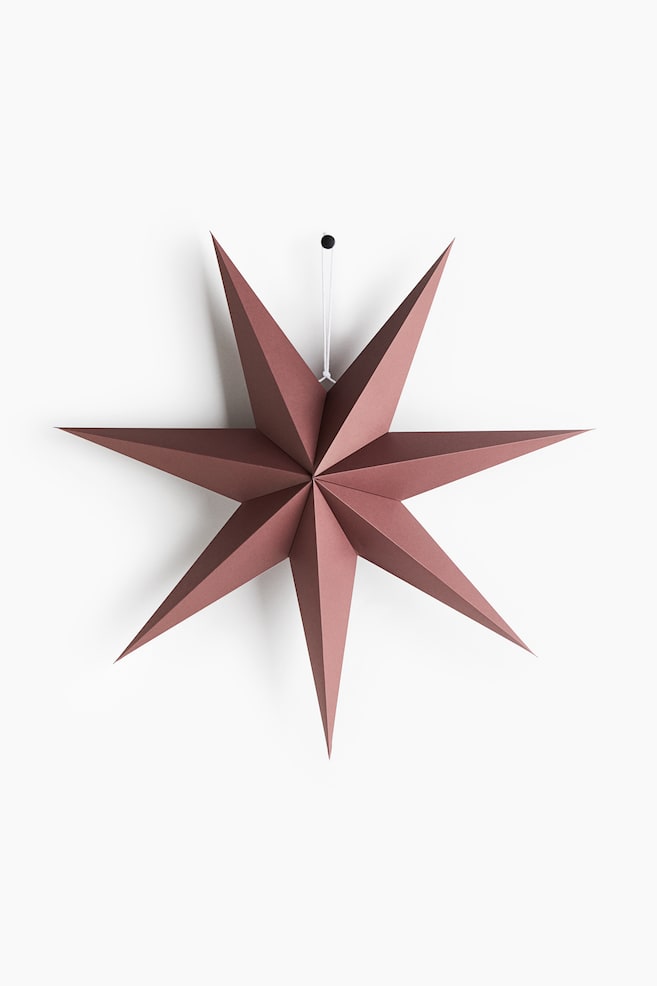 O decoraÈiune în formÄ de stea, de culoare roz prÄfuit, este orientatÄ spre faÈÄ, evidenÈiind un design tridimensional cu opt colÈuri, cu pliuri ascuÈite, geometrice. Steaua este suspendatÄ de un Ènur alb subÈire, ataÈat la o clemÄ micÄ neagrÄ. - 1
