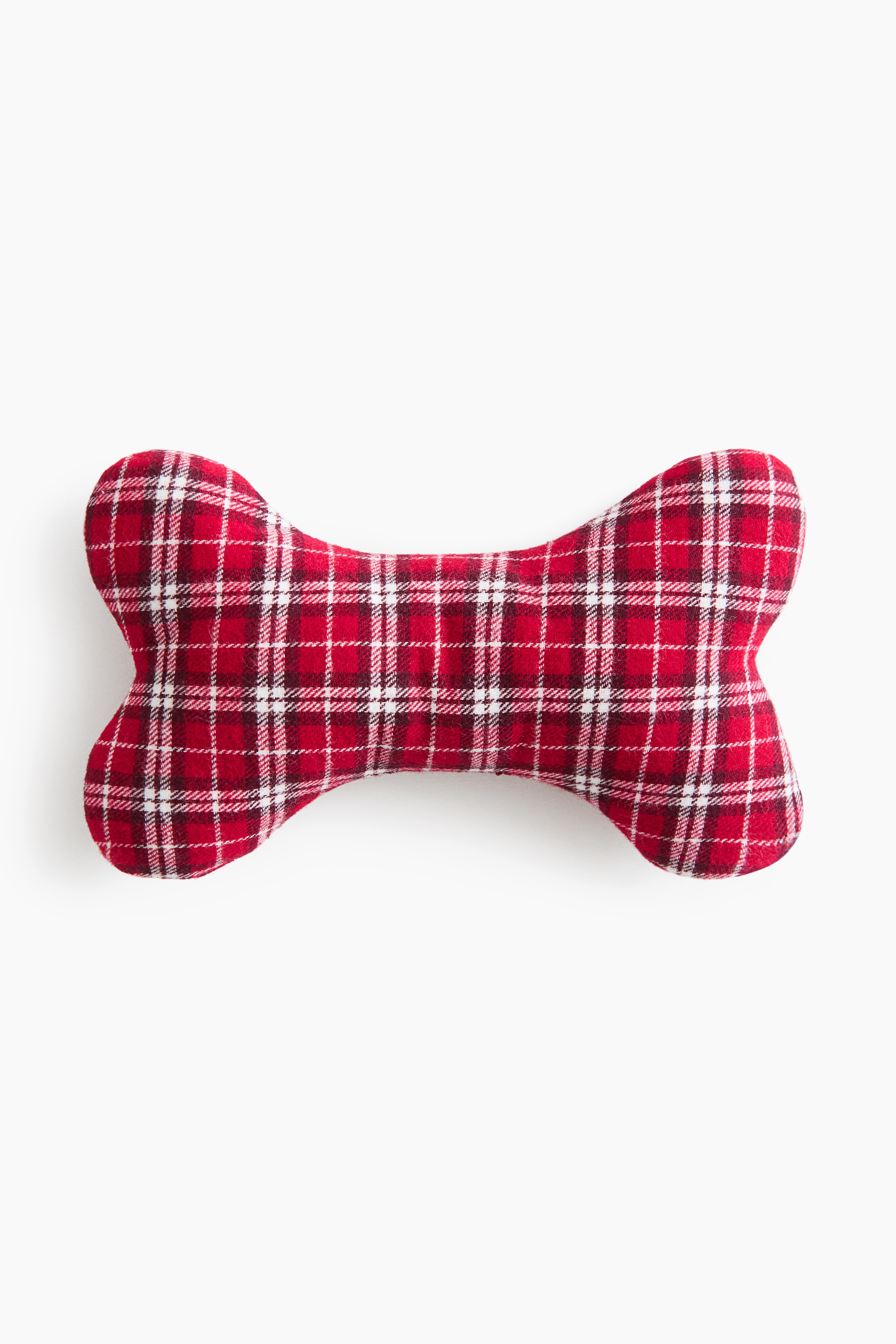 A bone-shaped padded pet toy made from a red and white checked woven fabric is lying on a light-coloured wooden floor, showcasing its rounded, stuffed design and stitched borders.