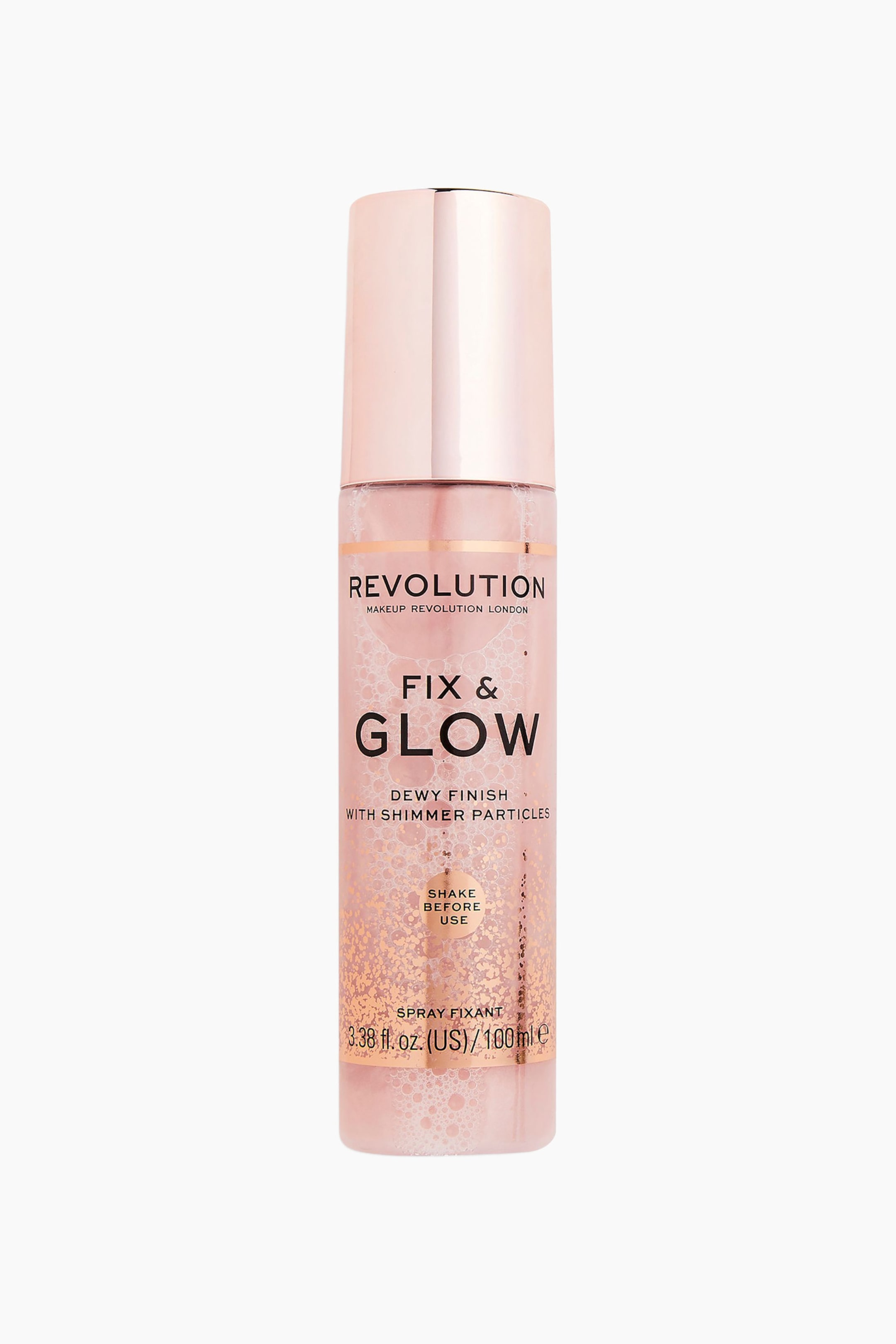 Visa större bild: Revolution Fix & Glow Setting Spray står upprätt och visar upp en transparent cylindrisk flaska fylld med en skimrande rosa vätska och toppad med ett metalliskt roséguldslock. På flaskans framsida syns svart varumärkestext och ett roséguldglittrigt mönster nära basen.