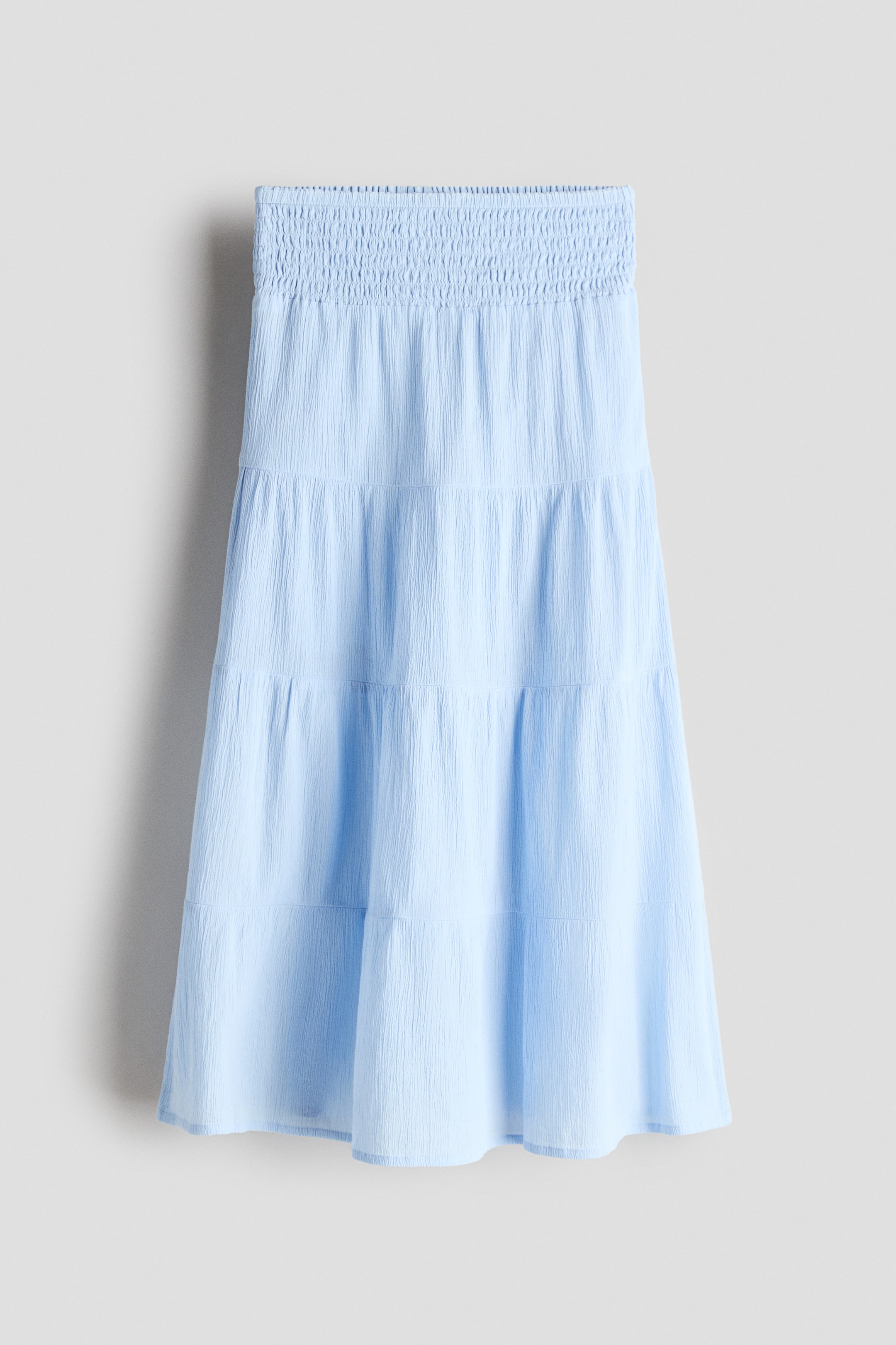 View larger image: Presenting a light blue tiered skirt from the FRONT, showcasing a smocked waistband and a crinkled texture.