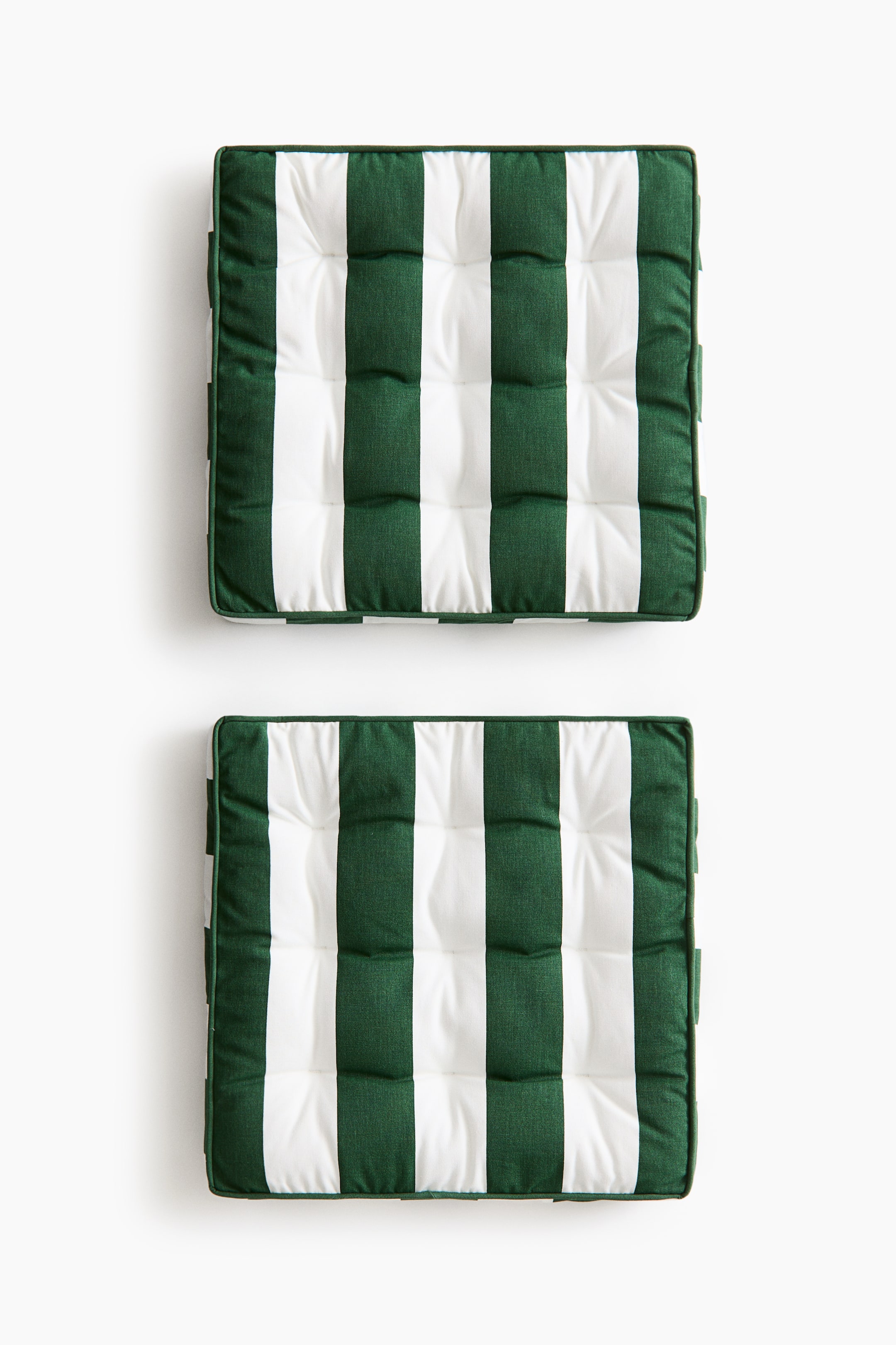 Ampliar la imagen: Dos cojines cuadrados presentan franjas verticales alternas en verde oscuro y blanco. Cada cojín está capitoneado con nueve hendiduras y terminado con bordes ribeteados.