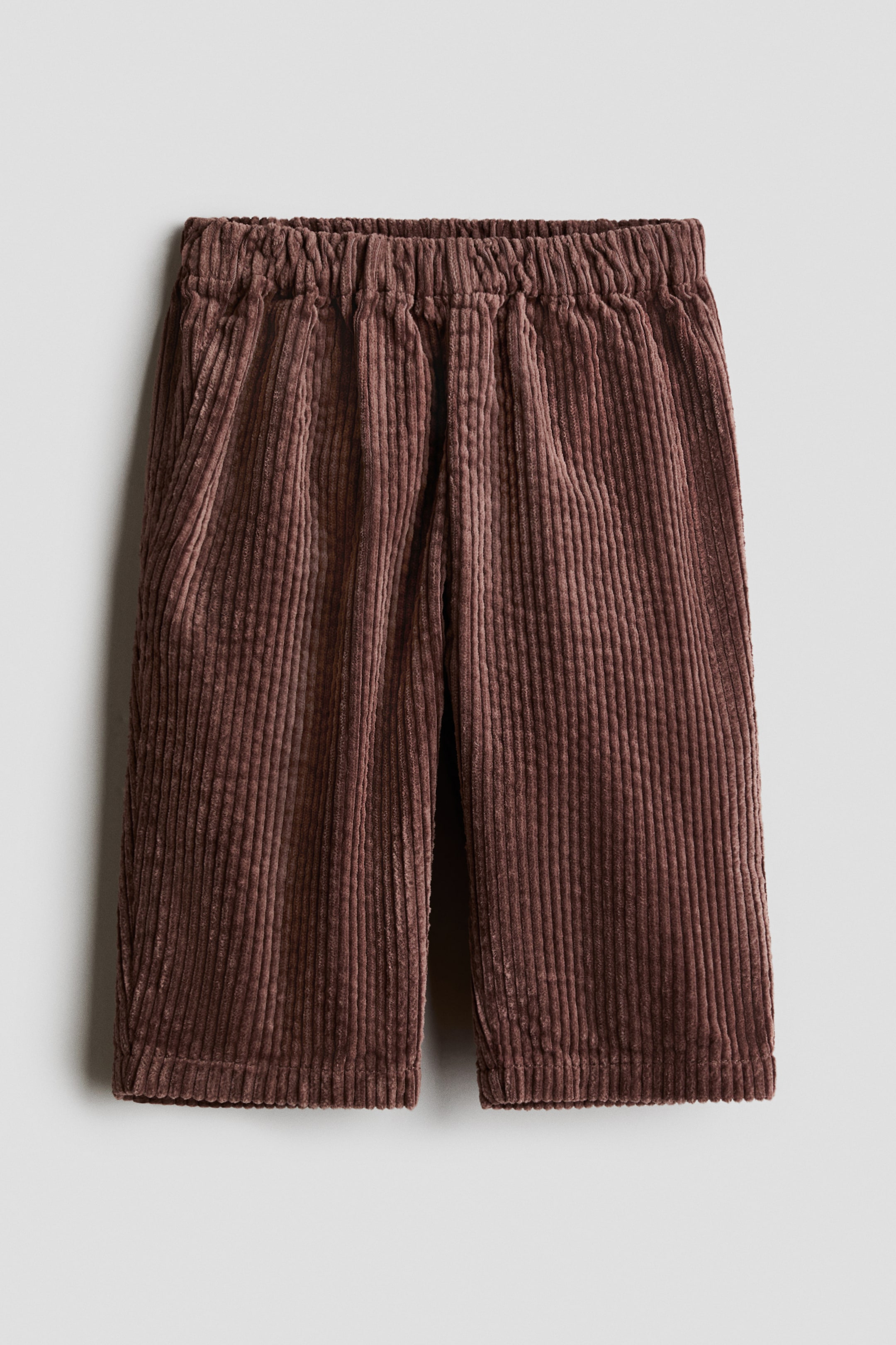 View larger image: Brown corduroy pants are laid flat, facing front, featuring an elasticated waistband and visible side pockets. They showcase a wide-wale corduroy texture and a straight-leg cut with a simple hem.