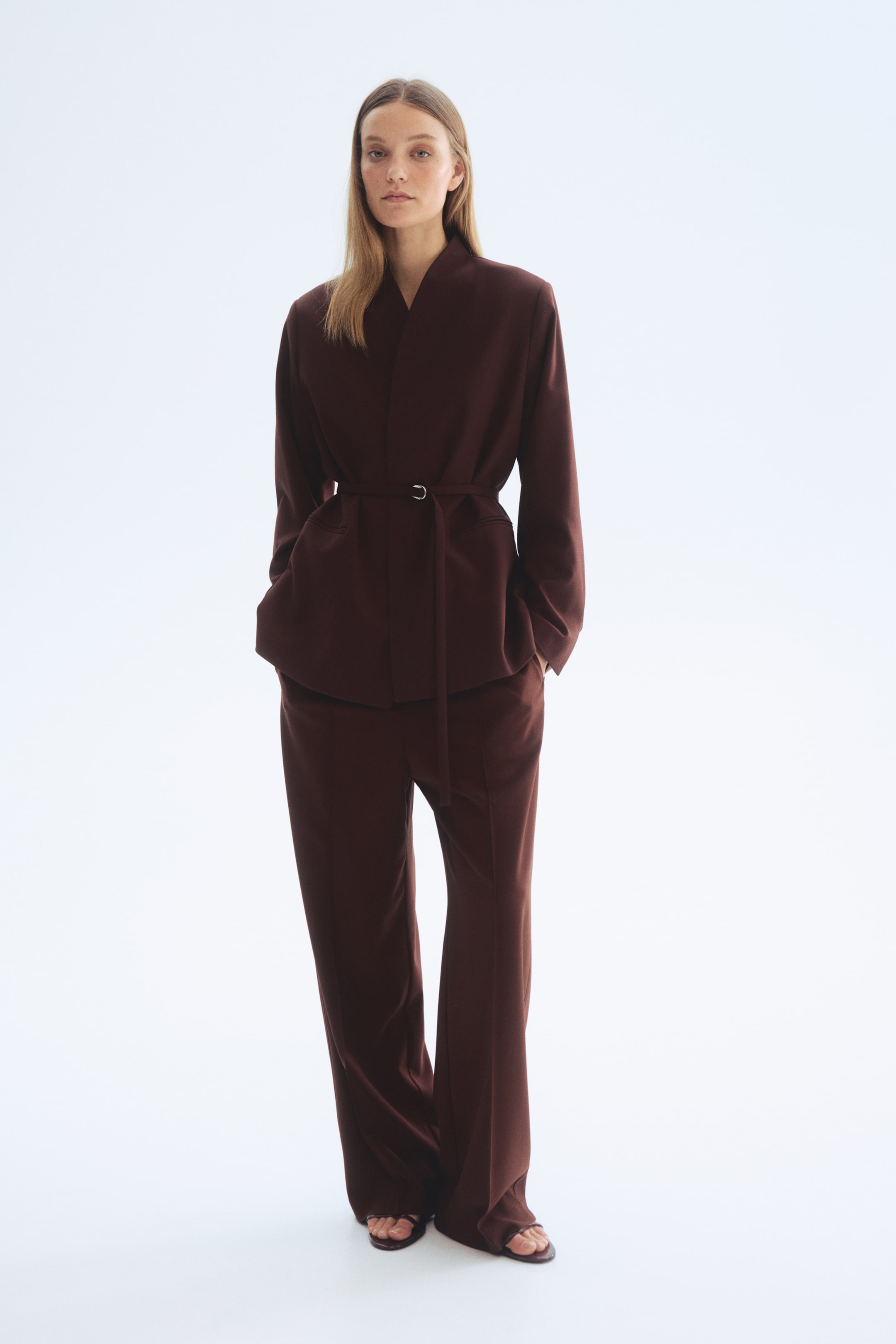 Näytä suurempi kuva: Tummanruskea kaksiosainen setti esillä, jossa on kimono-tyylinen yläosa V-kaula-aukolla ja vyötäröllä oleva vyö, yhdistettynä rentoihin leveälahkeisiin housuihin.