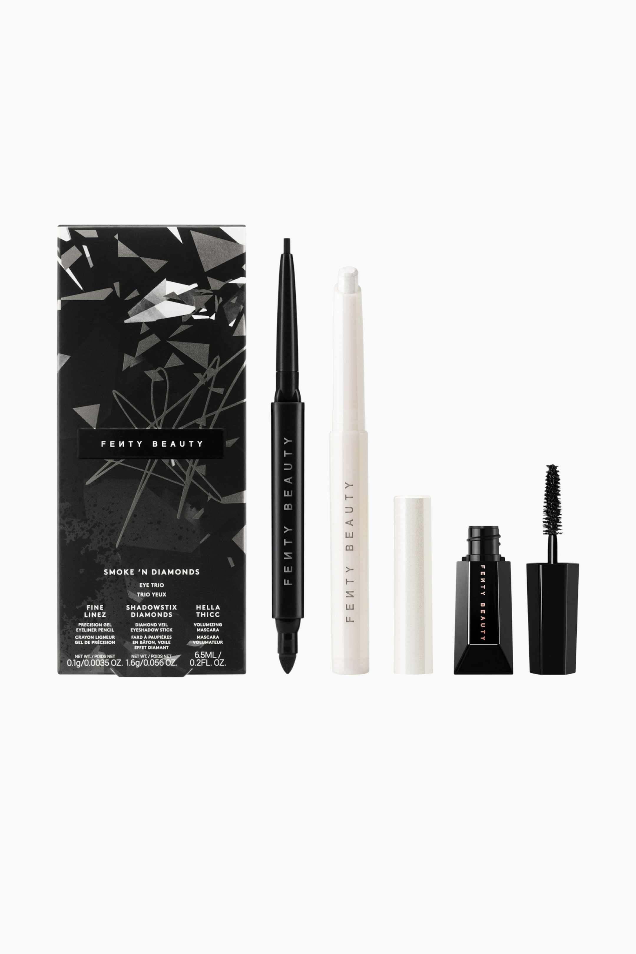 Visa större bild: Smoke'n Diamonds Eye Trio i begränsad upplaga visas med sin svarta förpackningsask med geometriskt mönster, tillsammans med sina tre makeup-produkter som står upprätt. Setet består av en svart eyelinerpenna med dubbla ändar som visar sin fina spets, en vit ögonskuggssticka utan kork som visar sin skimrande vita spets bredvid sin kork, samt en öppen svart mascaraflaska som står bredvid sin avskruvade borsthylsa.