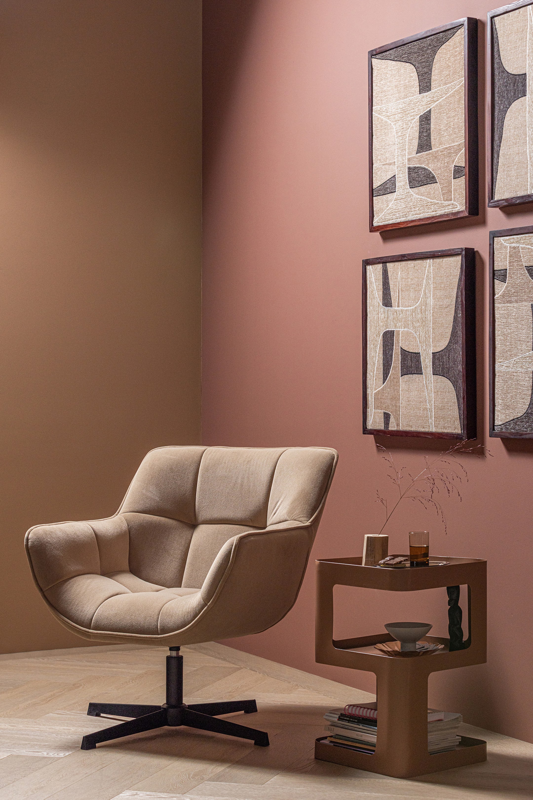Grotere afbeelding bekijken: Een beige gestoffeerde fauteuil presenteert zijn gebogen profiel met geïntegreerde armleuningen en een gecapitonneerde rug- en zitkussen, terwijl hij rust op een zwarte vierpotige draaivoet. De stoel is iets naar rechts gekanteld.