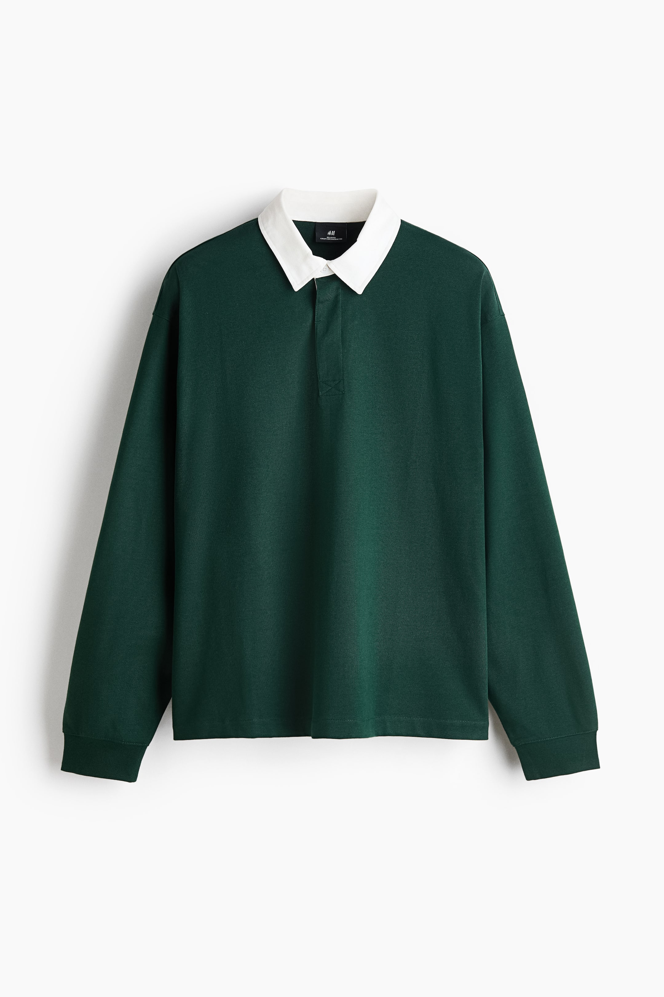 View larger image: A dark green, long-sleeved rugby shirt is shown from the front, featuring a contrasting white pointed collar and a concealed button placket. The shirt has a relaxed-fit silhouette with ribbed cuffs and a straight hem.
