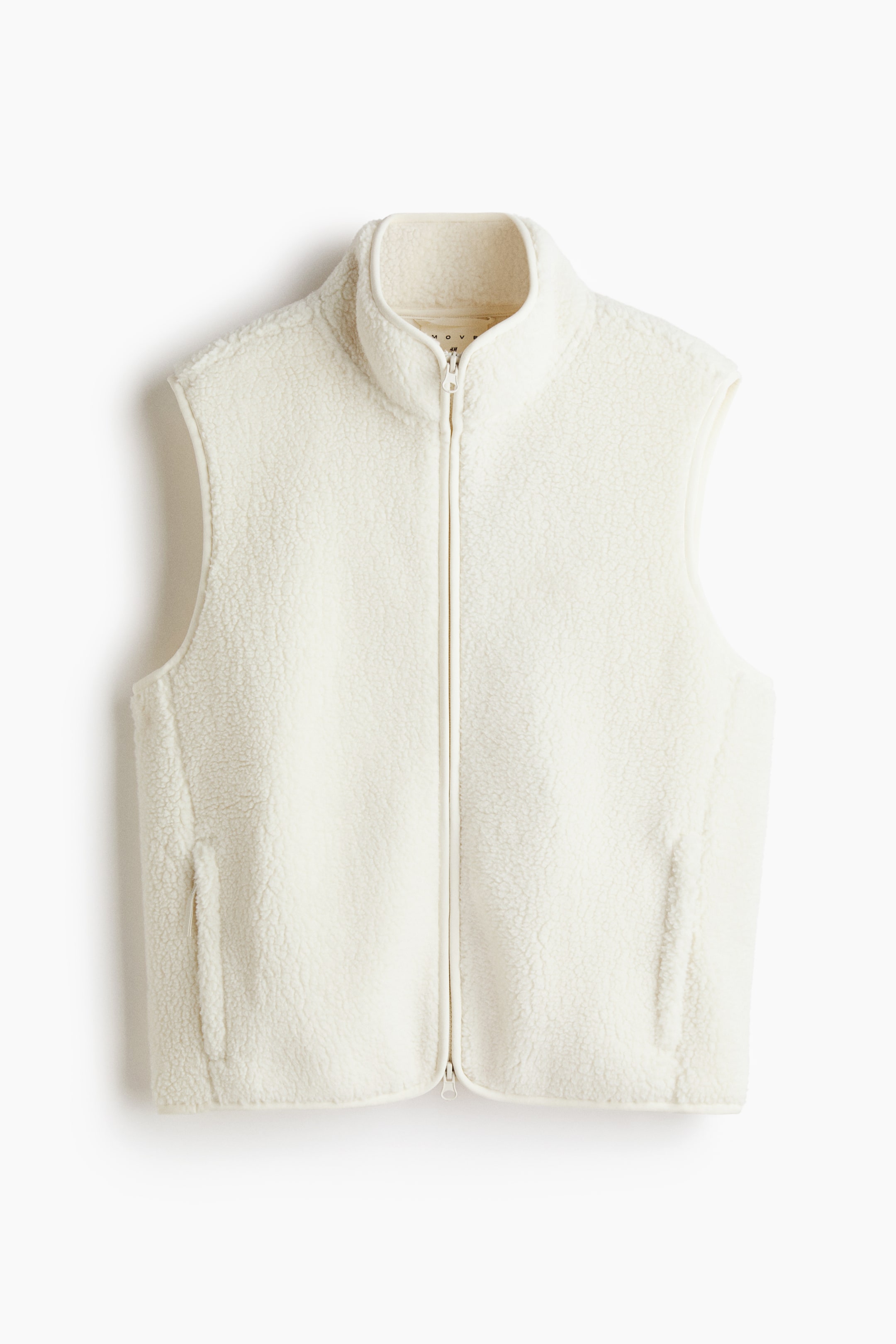 Vis større bilde: En FRONT off-white sherpa fleecevest har en hel glidelås som går nedover midten. Den har en oppstående krage og to vertikale lommer med åpning foran.