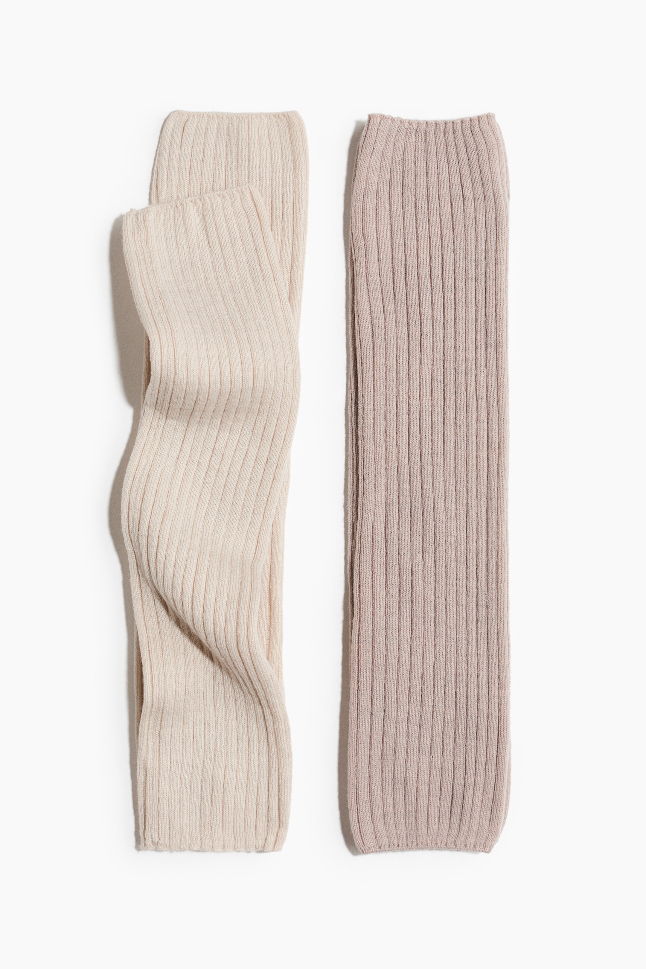 Visa större bild: Benvärmare visar en mjuk ribbstickad textur när de ligger platt. En ljus beige benvärmare är försiktigt böjd, och en ljus taupe benvärmare ligger rakt bredvid.