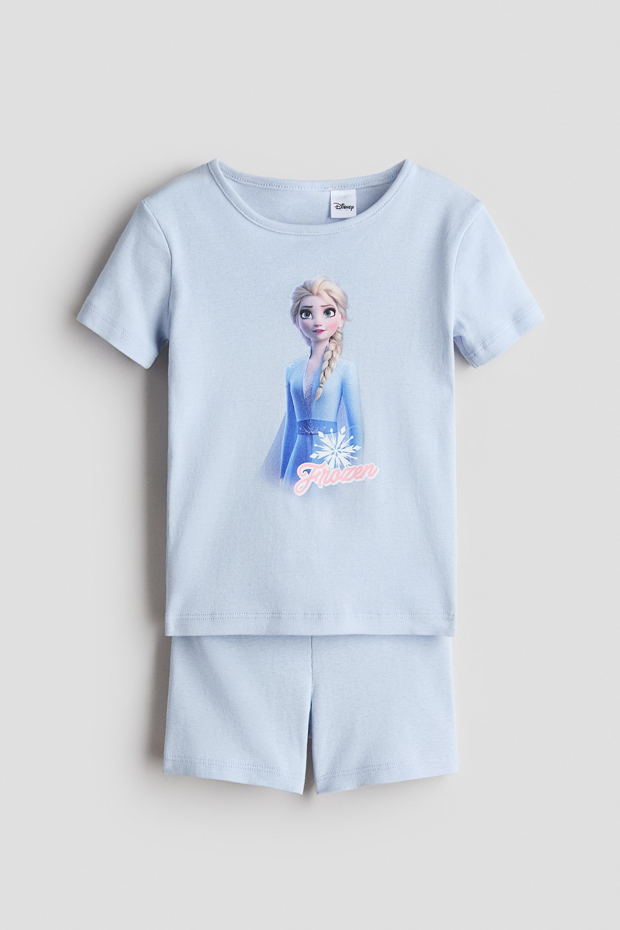 View larger image: A light blue printed cotton jersey pajama set is shown from the front. The top features a round, rib-trimmed neckline, short sleeves, and a print of Elsa from Frozen with a snowflake and the "Frozen" text, while the matching shorts have a covered elastic waistband.