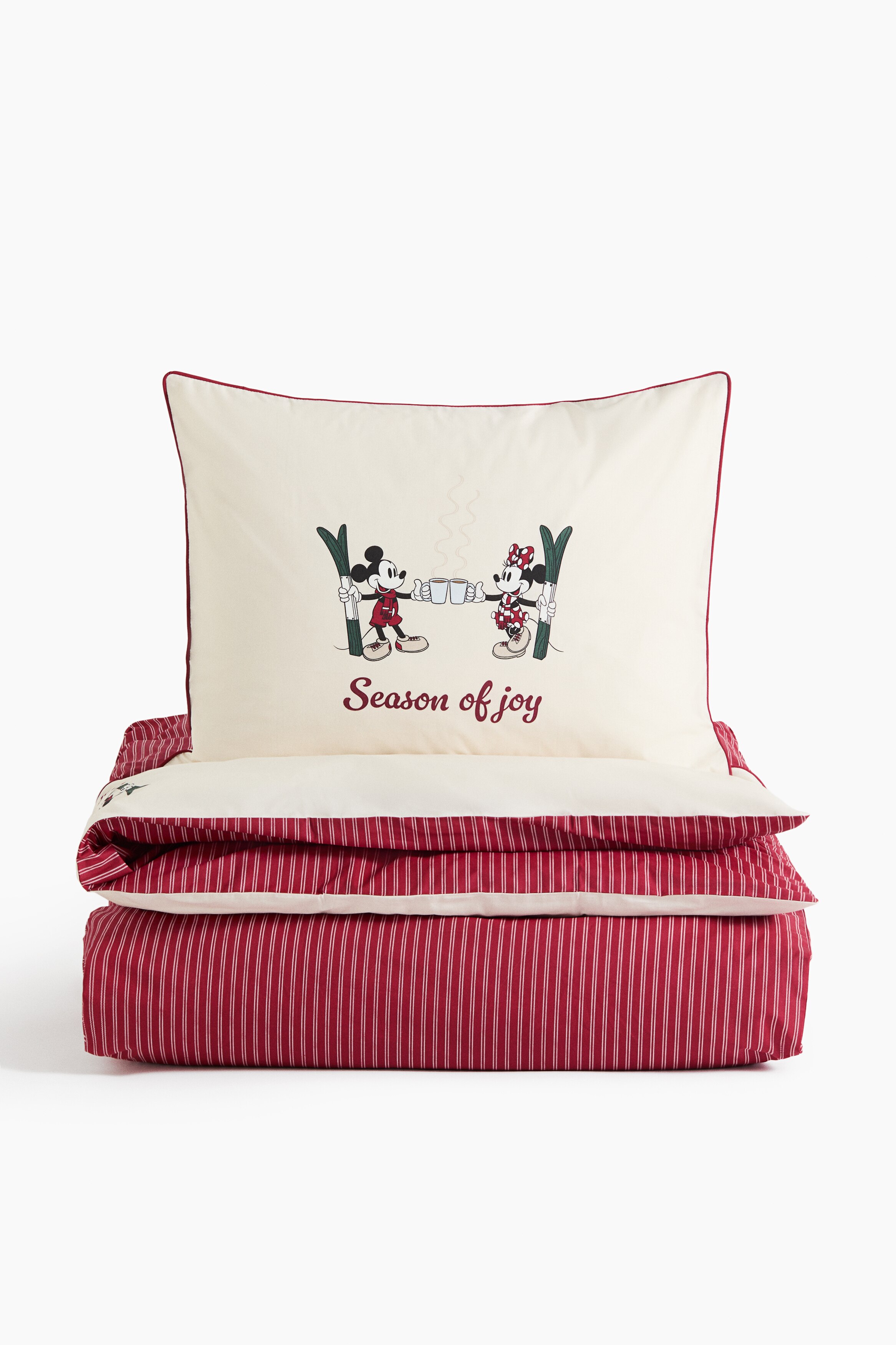 A cotton percale quilt cover set is dressing a bed, featuring a red and white vertically striped quilt cover with a folded-over solid white panel at the top. The matching white pillowcase is displaying a central cartoon character illustration and red piping along the edges.