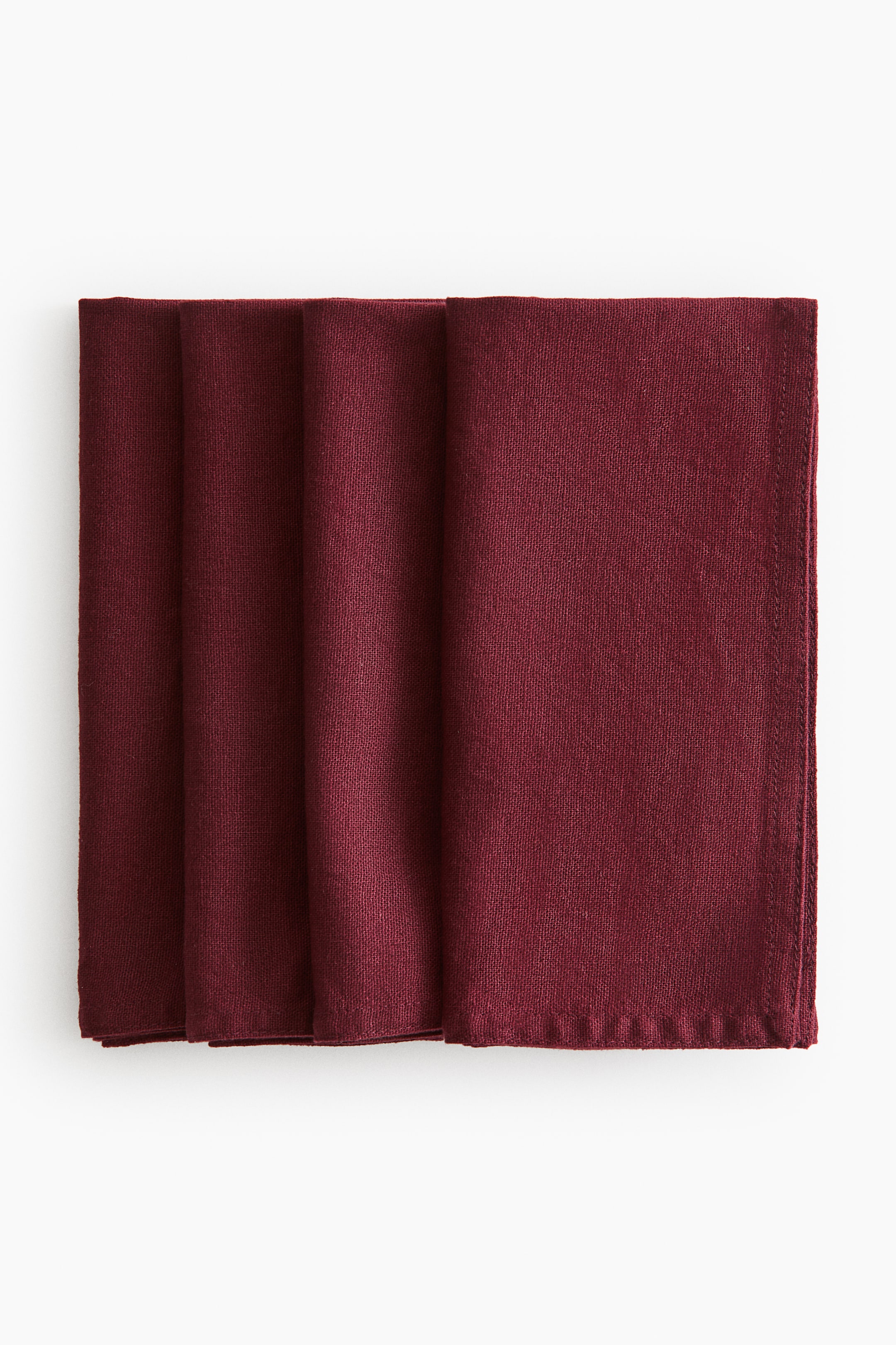 View larger image: Four deep red napkins are folded and stacked, showing their front surfaces. Each napkin displays a visible, slightly textured weave with neatly finished edges.