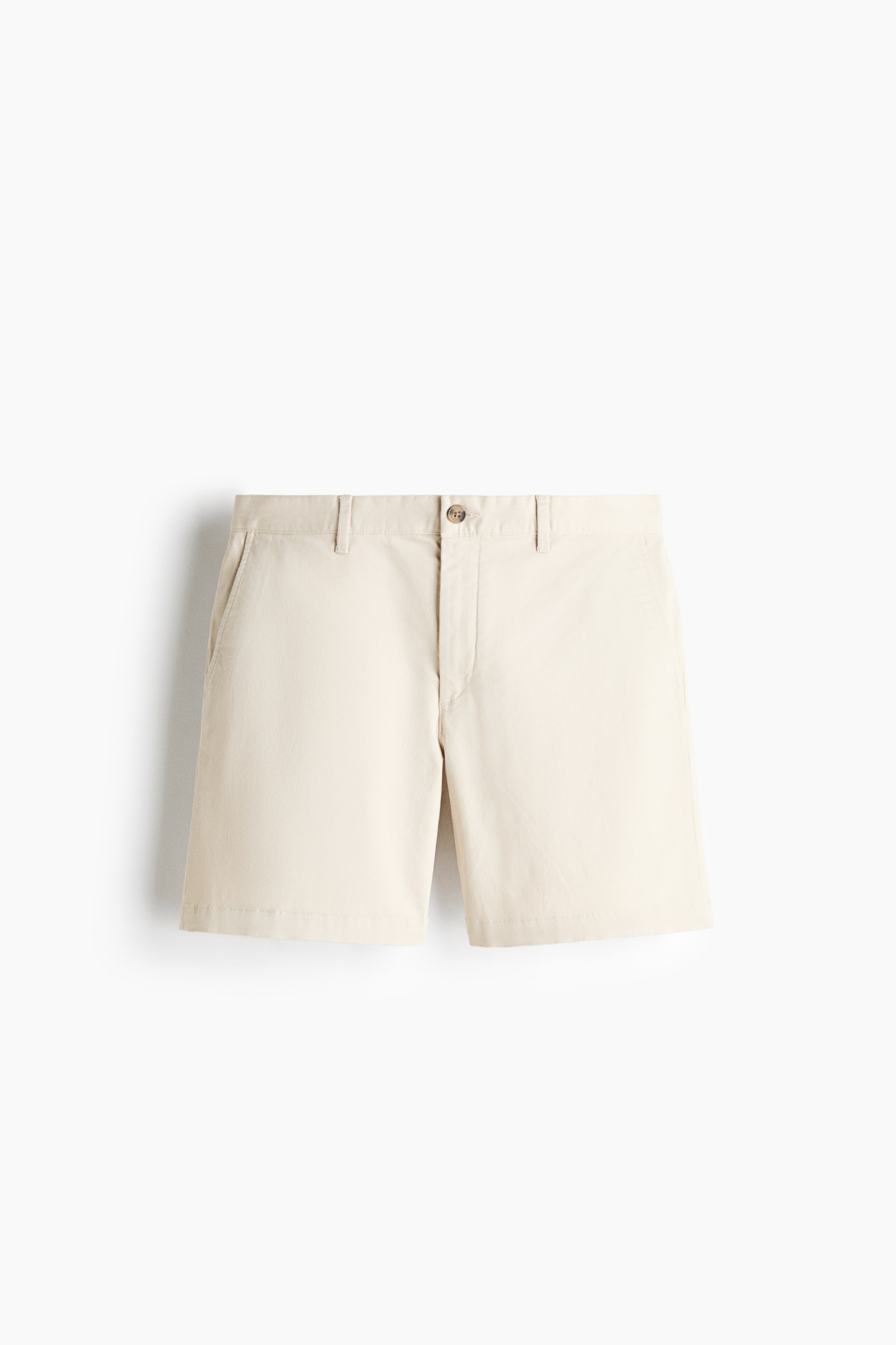 Xem ảnh lớn hơn: Một chiếc quần short chino màu kem được chụp từ phía trước, nổi bật với cạp quần có đỉa thắt lưng, một khuy cài đơn và túi chéo hai bên. Quần short có phom regular fit và gấu thẳng, được làm từ vải cotton twill có độ đứng form.