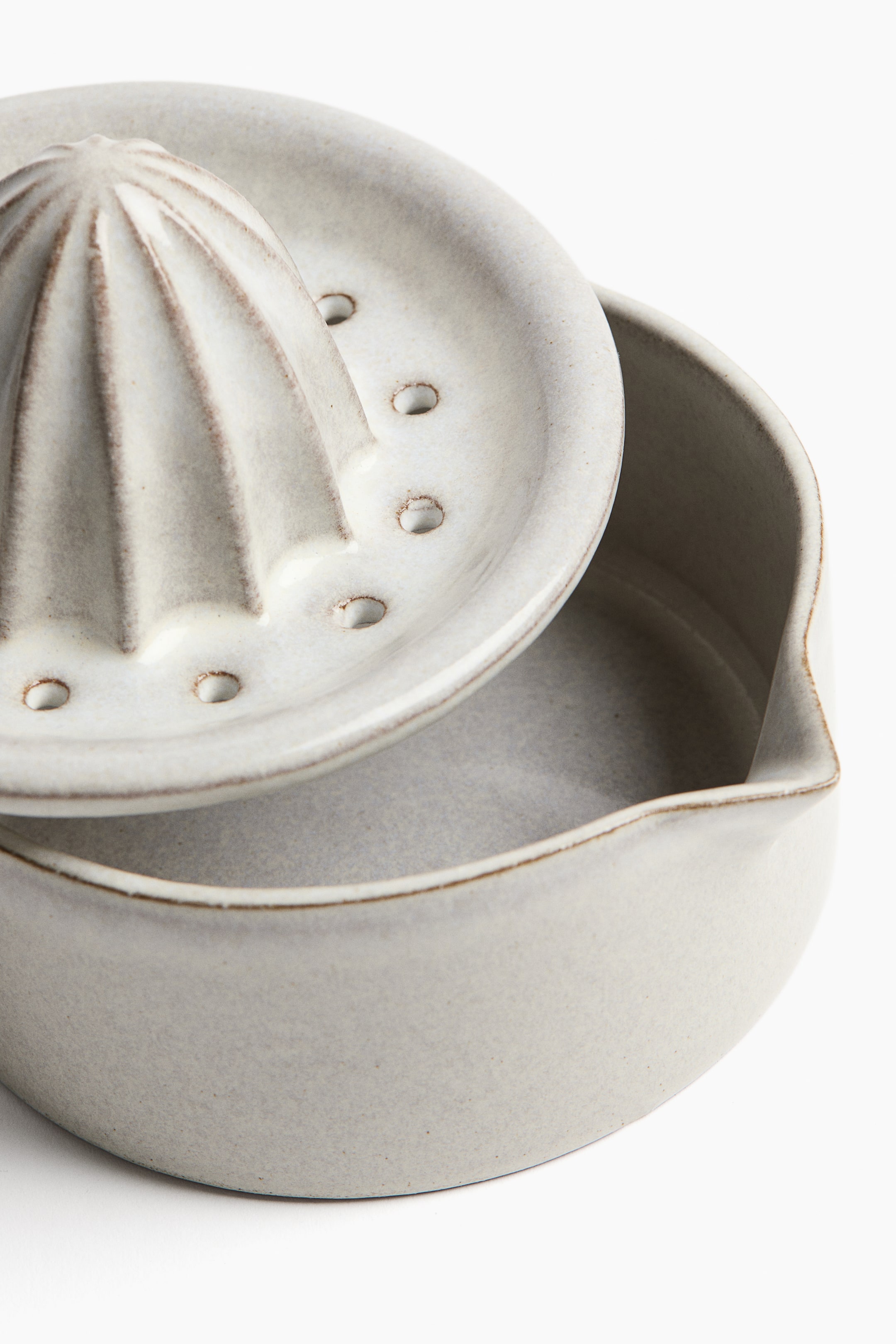 Grösseres Bild ansehen: Ein gesprenkelter, cremefarbener Keramik-Zitrusentsafter mit einem Reibaufsatz, der über radiale Rillen und Abflusslöcher verfügt und auf einem schalenförmigen Sockel mit Ausguss ruht.