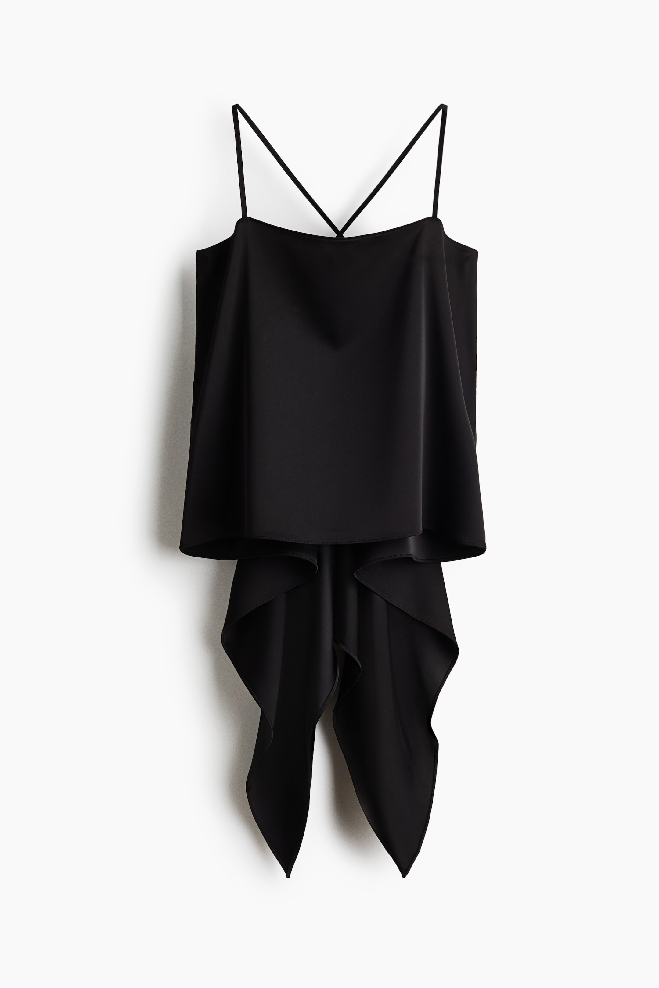 Grotere afbeelding bekijken: Een zwarte camisole-top hangt met de voorkant naar voren en laat smalle spaghettibandjes zien die over de borst kruisen. De soepele stof valt in een gelaagd silhouet, met lange, asymmetrische banen die onder de rechte zoomlijn naar beneden vloeien.