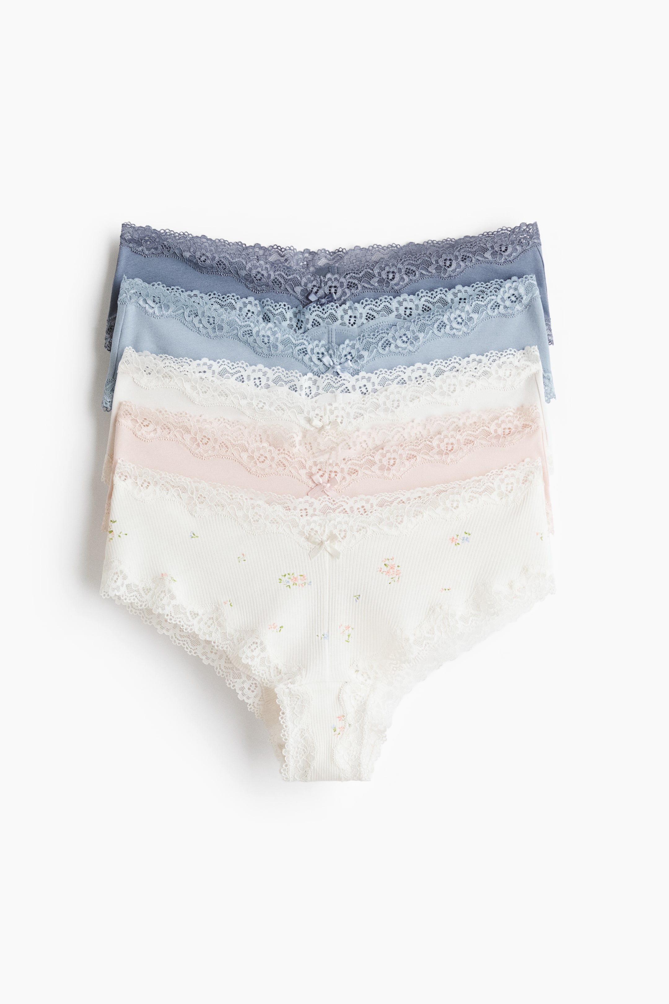 查看大圖: 四件內褲疊放在一起，每件內褲採用柔軟的棉質平紋布，邊緣飾有蕾絲，腰部為低腰V字形，正前方有一個小蝴蝶結。內褲的顏色分別為深藍色、淺藍色、粉色和白色，其中白色款式上有細緻的花卉圖案。
