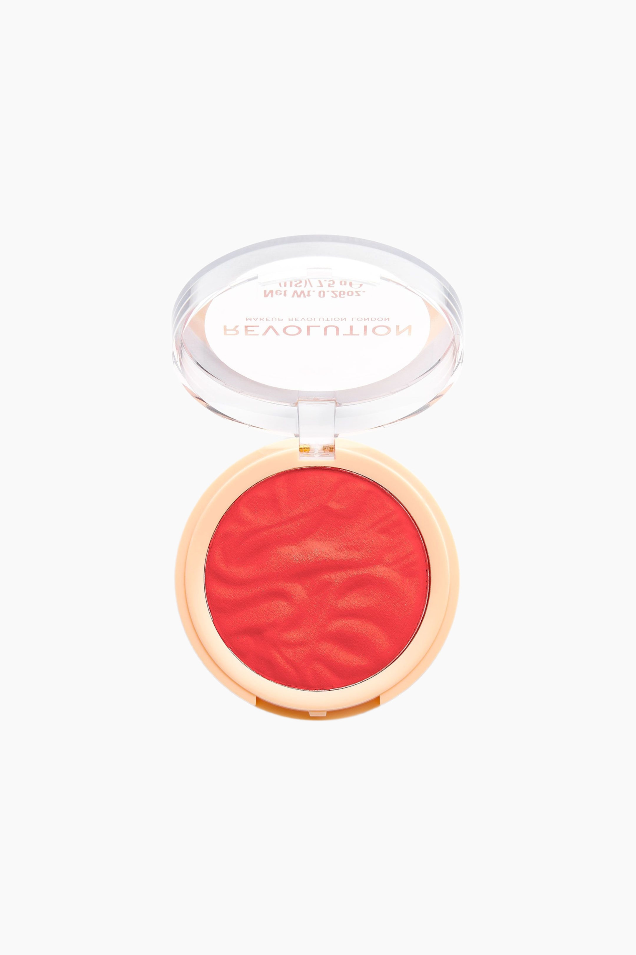 Se større billede: En rund blush-kompakt præsenterer et levende koralrødt pudder med et bølget, tekstureret mønster i en lys beige base. Det klare plastlåg er slået op og vender opad, så brandnavnet er synligt på den indvendige overflade.