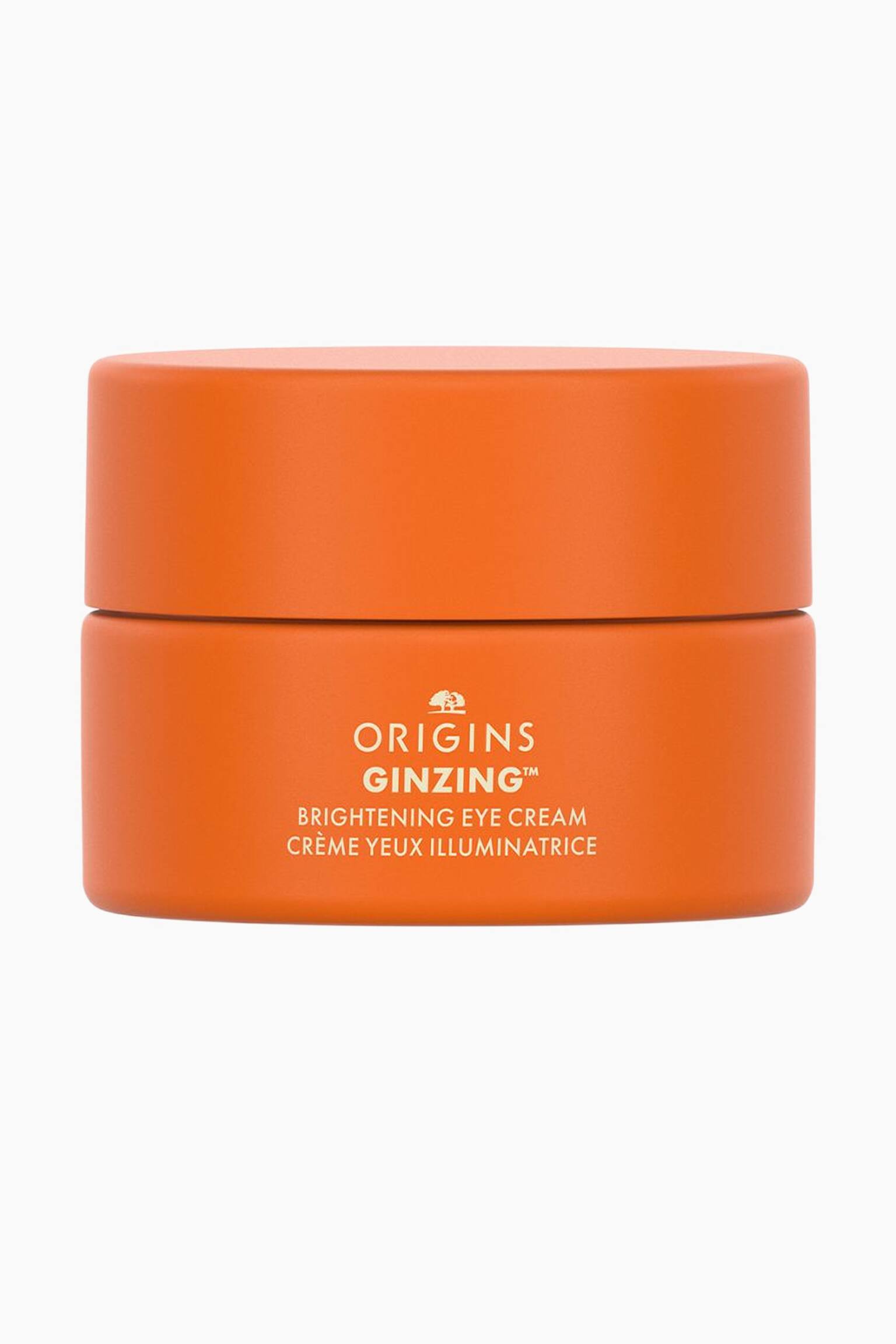 En liten, cylindrisk matt orange burk med Origins GinZing Brightening Eye Cream stÃ¥r upprÃ¤tt och vÃ¤nd framÃ¥t med det matchande orange locket stÃ¤ngt. Framsidan av burken visar grÃ¤ddfÃ¤rgad text som lyder "ORIGINS GINZING? BRIGHTENING EYE CREAM" och "CRï¿½ME YEUX ILLUMINATRICE" under varumÃ¤rkets trÃ¤logo.