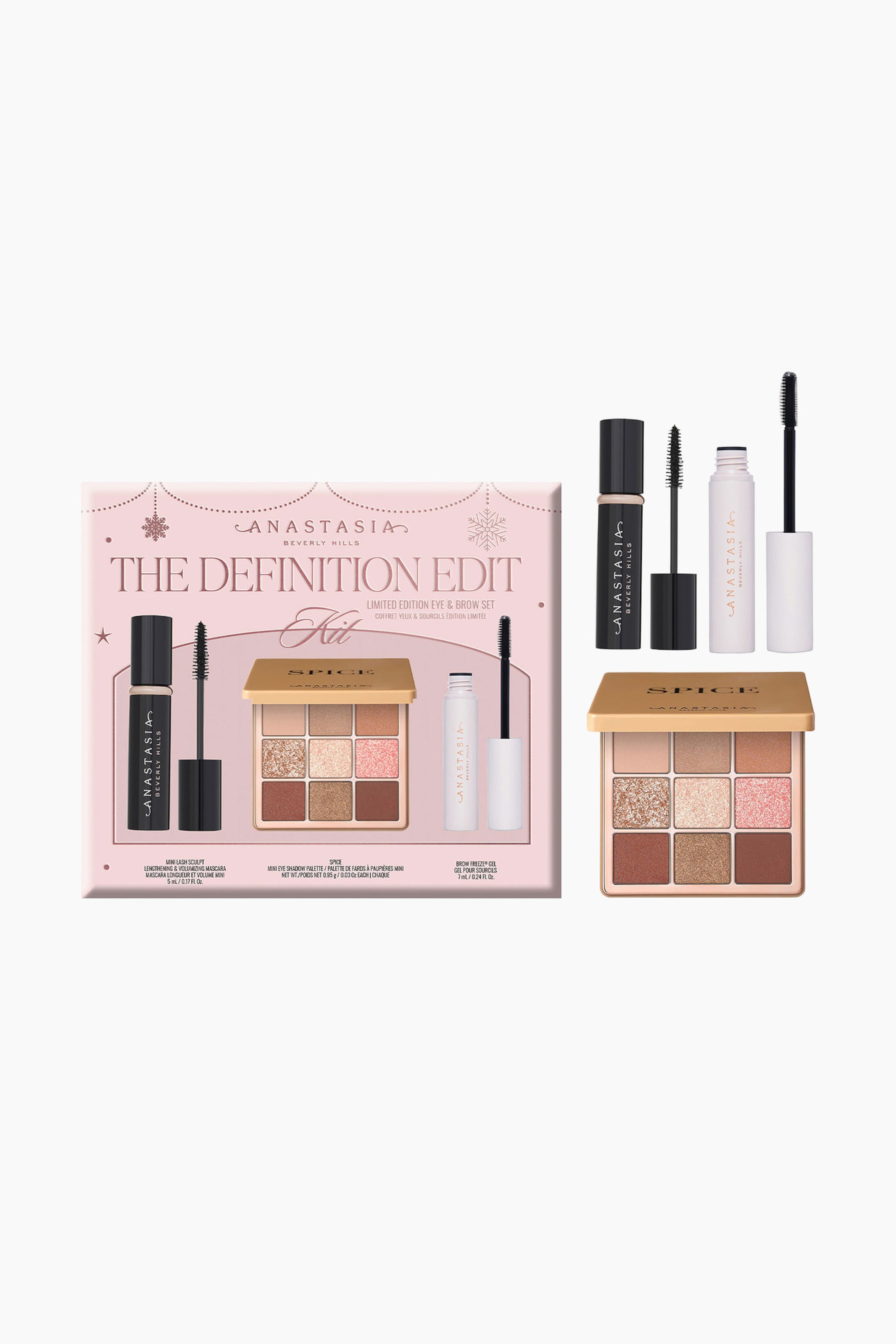 Visa större bild: Anastasia Beverly Hills sminkset "The Definition Edit" visas i sin ljusrosa förpackningsask tillsammans med de medföljande produkterna: en öppen ögonskuggspalett med nio nyanser, "Spice", med ett guldfärgat lock, en svart minitub med mascara där borsten är skruvad ur, samt en vit minitub med brow gel där borsten är skruvad ur.
