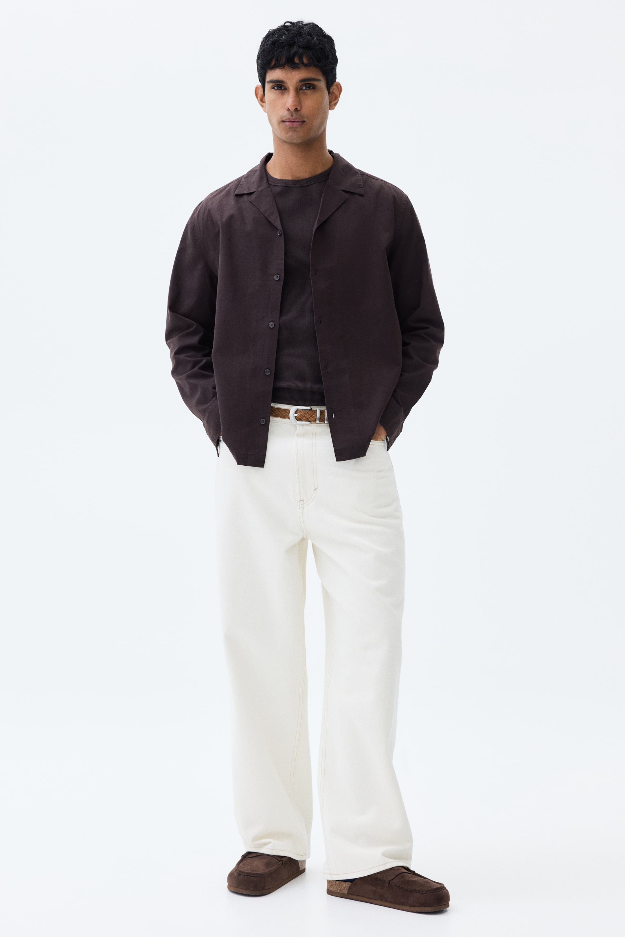 View larger image: The model is sporting a deep brown long-sleeved shirt crafted from a cotton and linen blend. This shirt is designed with a resort collar, French front, buttoned cuffs, and a straight-cut hem, styled open over a dark t-shirt.