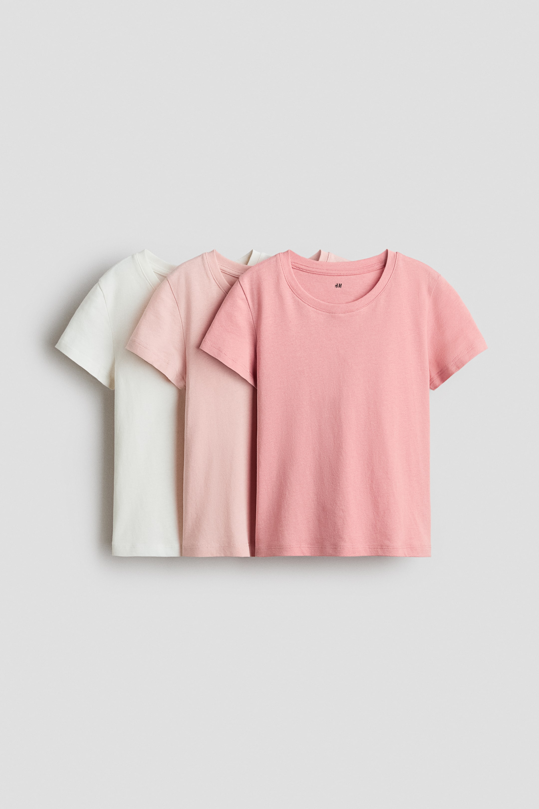 View larger image: A set of three short-sleeved t-shirts is showcasing its front view, featuring white, light pink, and pink colors. Each t-shirt is crafted with a round, ribbed neckline and a straight hem.