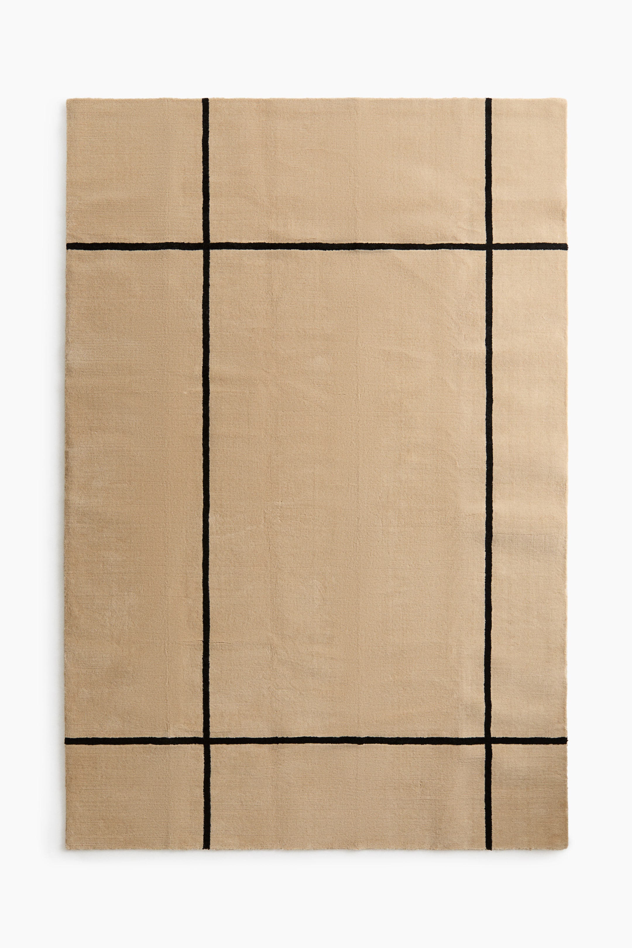 View larger image: A rectangular rug presents a beige field with a black geometric pattern. The pattern consists of two vertical and two horizontal black lines, appearing as raised lines outlining a central rectangular area.