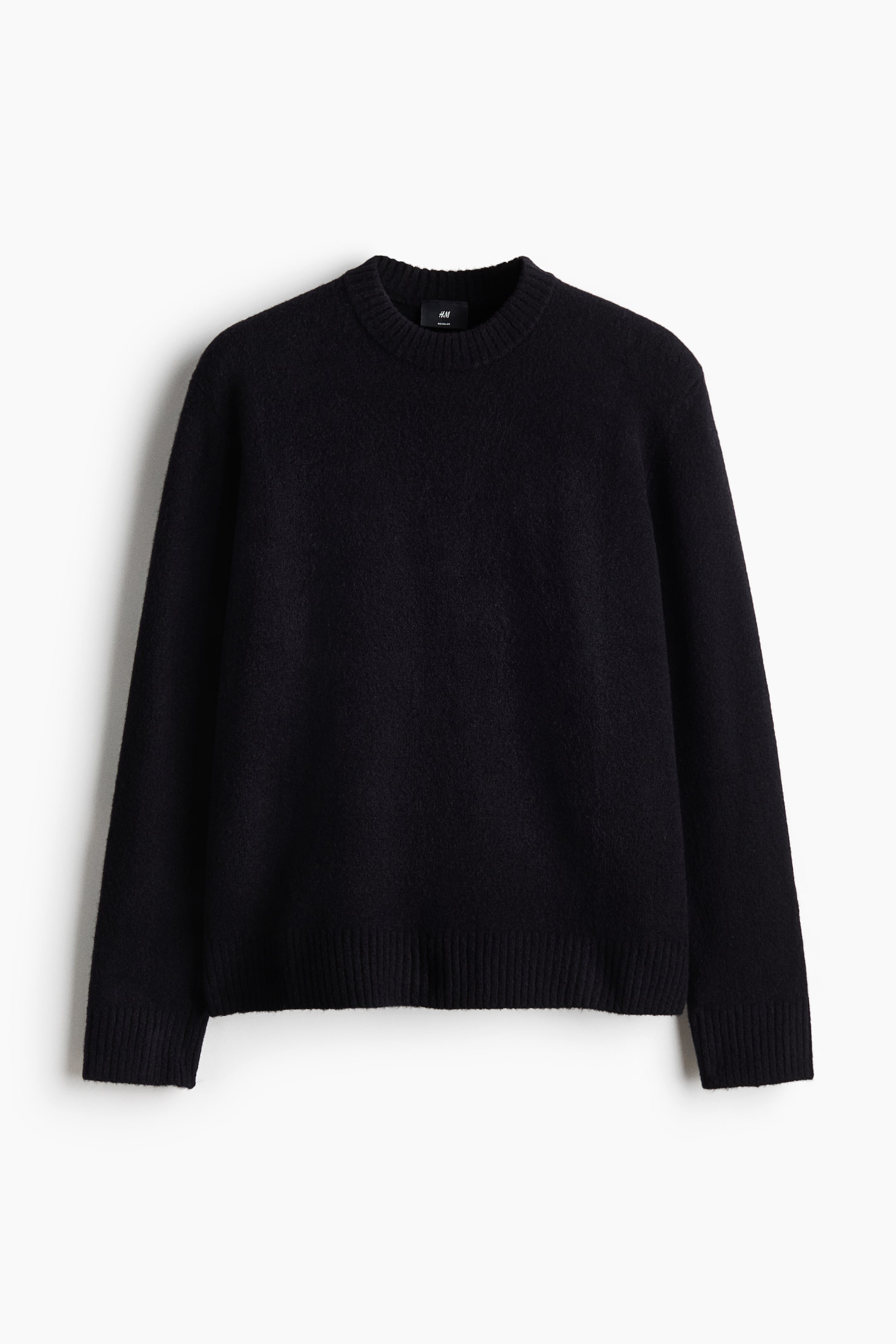 View larger image: A black crew neck sweater is showcased, facing forward. It features a soft, textured knit with ribbed cuffs and a ribbed hem.