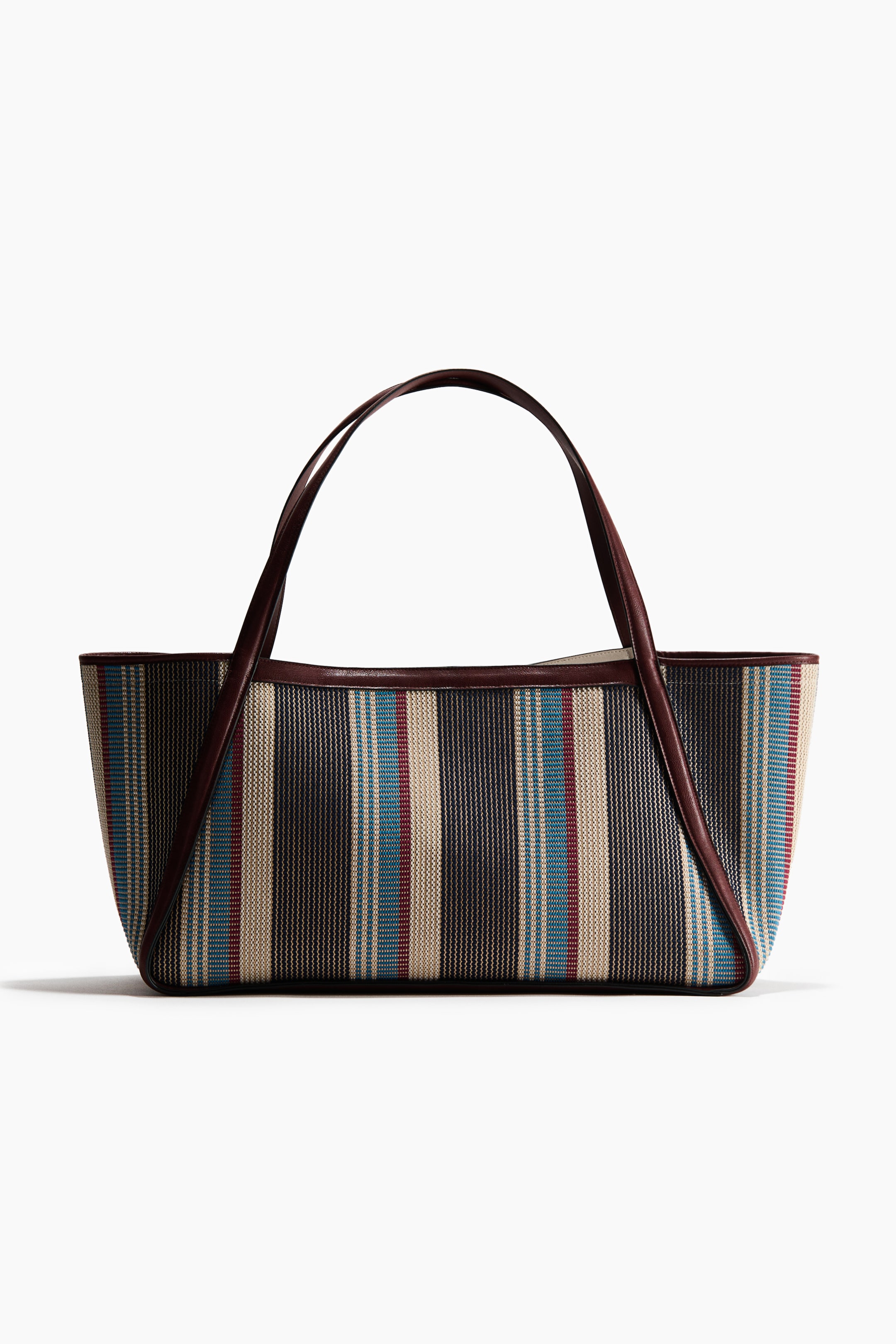 View larger image: A woven striped tote bag showcases its front, adorned with vertical stripes in dark brown, beige, blue, and red. It is crafted with dark brown handles and matching trim outlining the top and bottom edges.