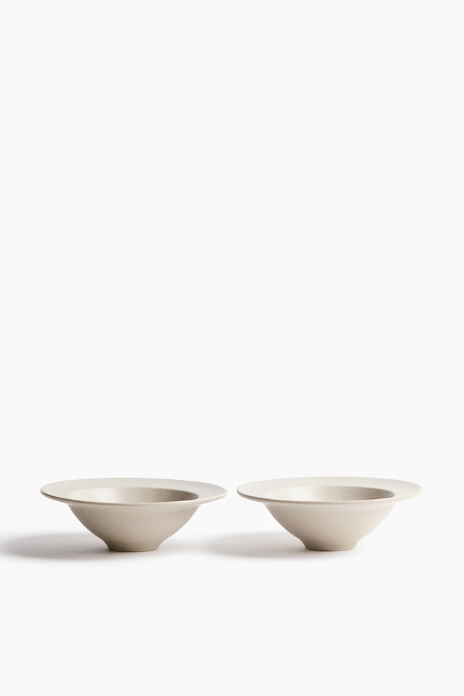 Deux bols en céramique blanc cassé sont placés côte à côte, mettant en valeur une silhouette conique effilée qui sâévase vers un large rebord plat. Les bols présentent un émail mat à la texture fine et sont photographiés de face. - 1