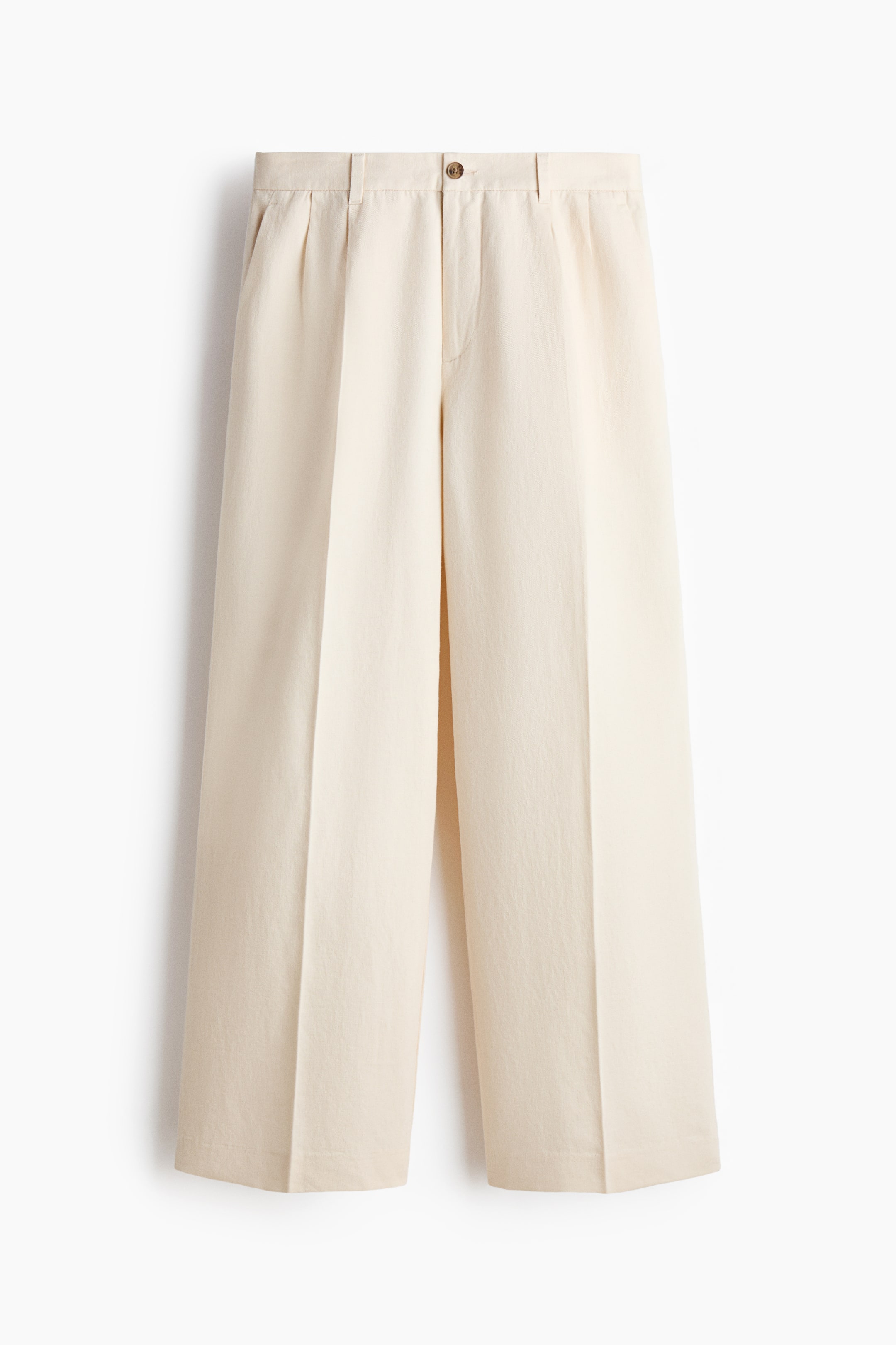 View larger image: Cream-colored wide-leg pants are presenting from the front, featuring a flat waistband with belt loops, a single brown button closure, and single front pleats. A visible crease is running down each wide leg.