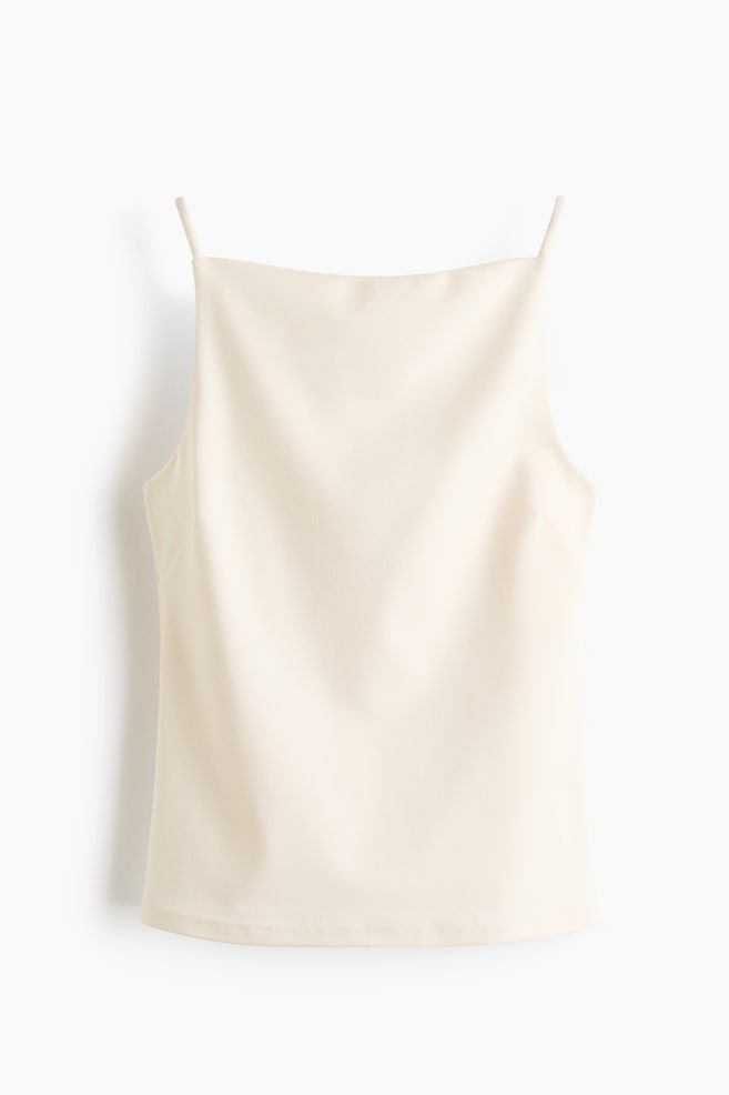 Un top ajustado de color crema en jersey grueso se muestra desde el frente. Presenta un escote cuadrado con un corte estrecho en la parte superior, tirantes finos y pinzas visibles en el busto. - 1
