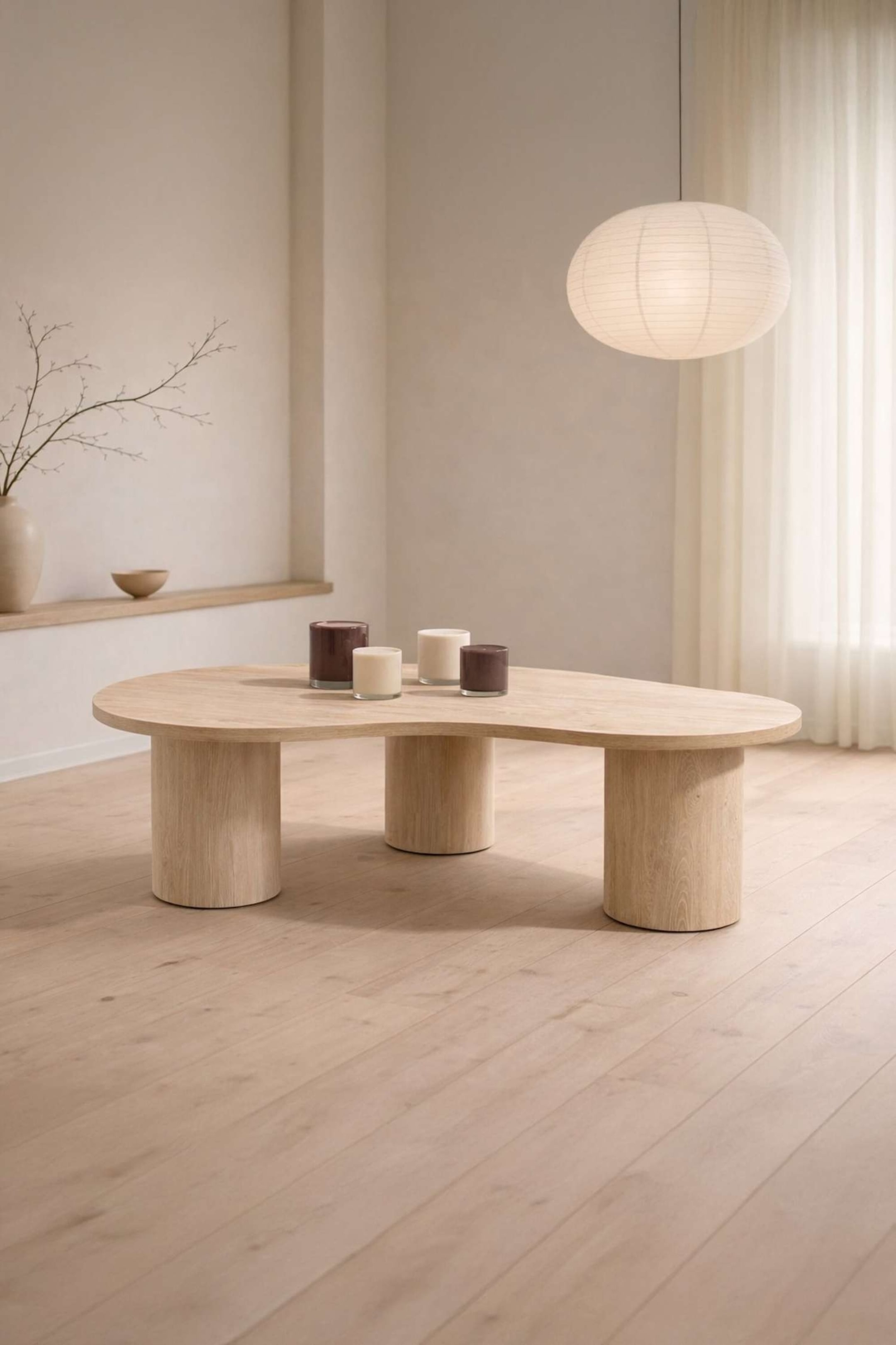 Visualizza immagine più grande: Un tavolino da caffè in legno chiaro presenta un piano organico a forma di fagiolo poggiato su tre spesse gambe cilindriche, con quattro candele posizionate sulla sua superficie.