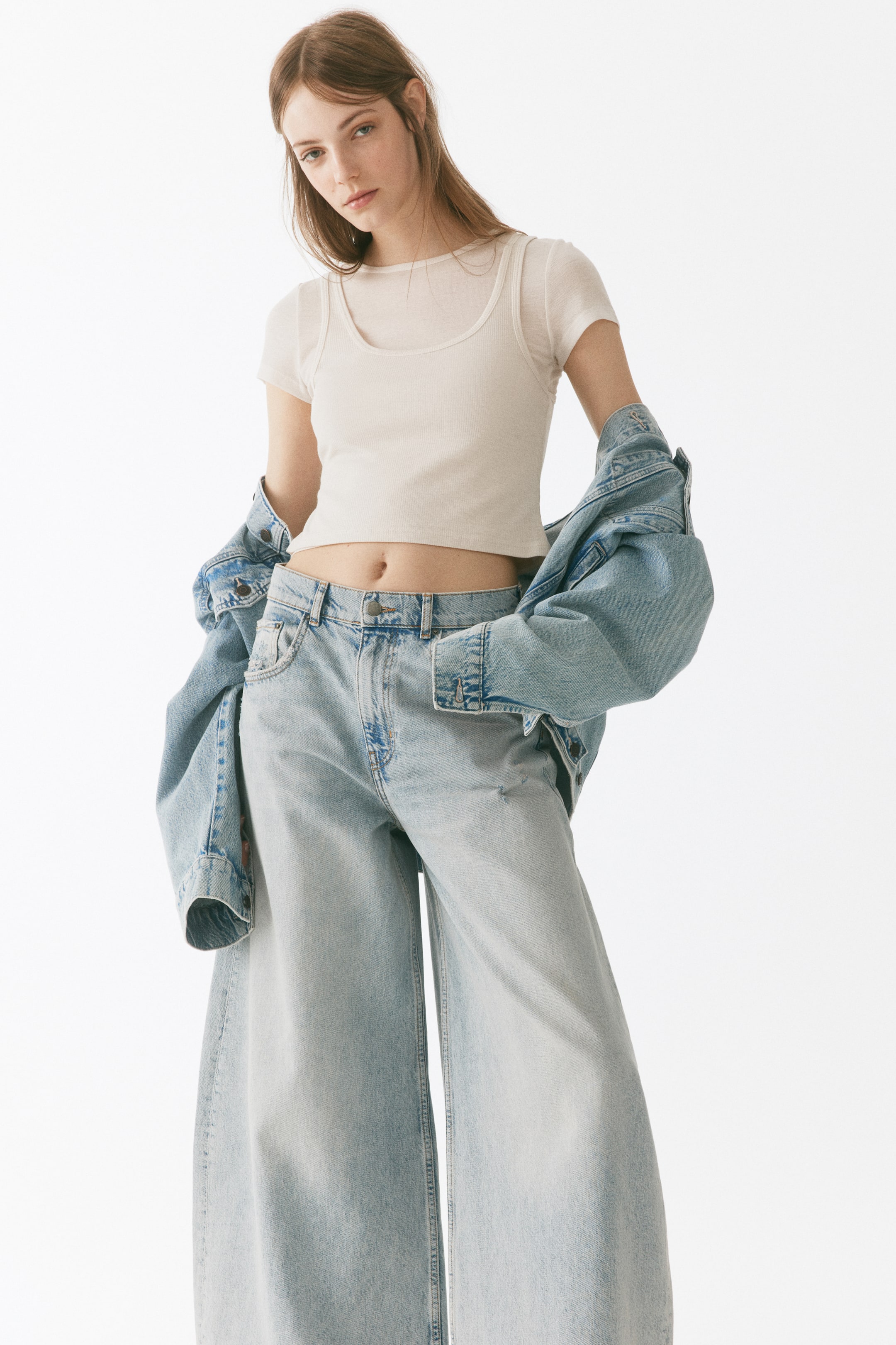View larger image: The light wash wide-leg jeans showcase a faded light blue denim finish, highlighting a wide-leg silhouette from a front-facing perspective. They exhibit distressed details on the upper thigh and feature visible belt loops at the waist.
